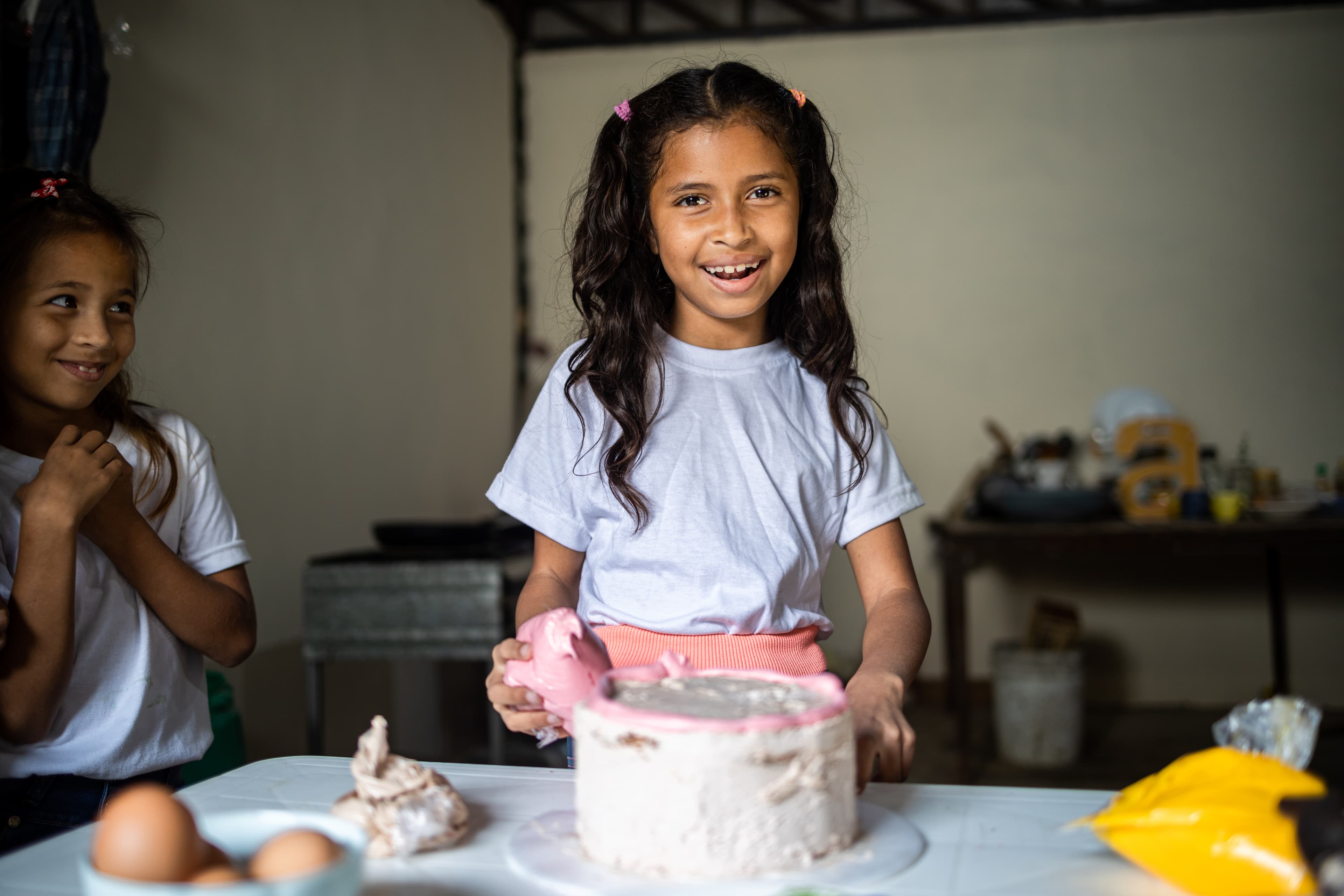 A young girl is smiling as she decorates a cake at the child development center.