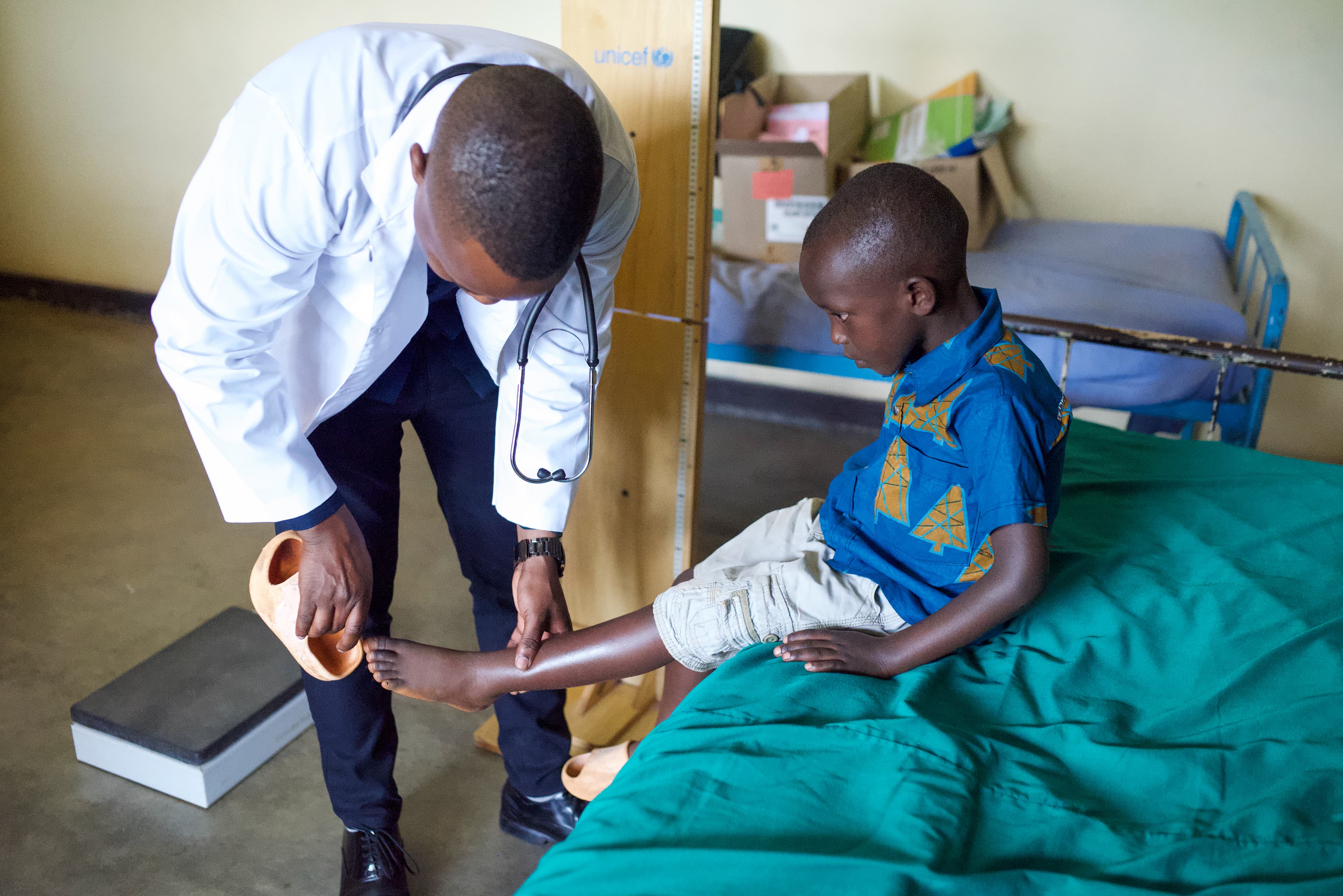 A doctor is checking a young boy’s leg during his medical checkup.