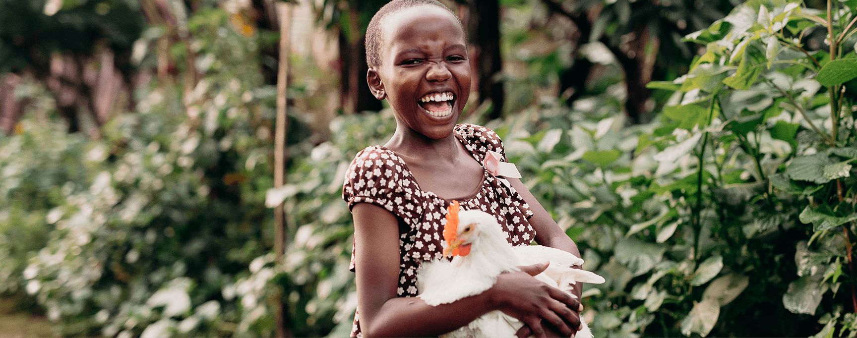 Girl holds a chicken while laughing towards the camera