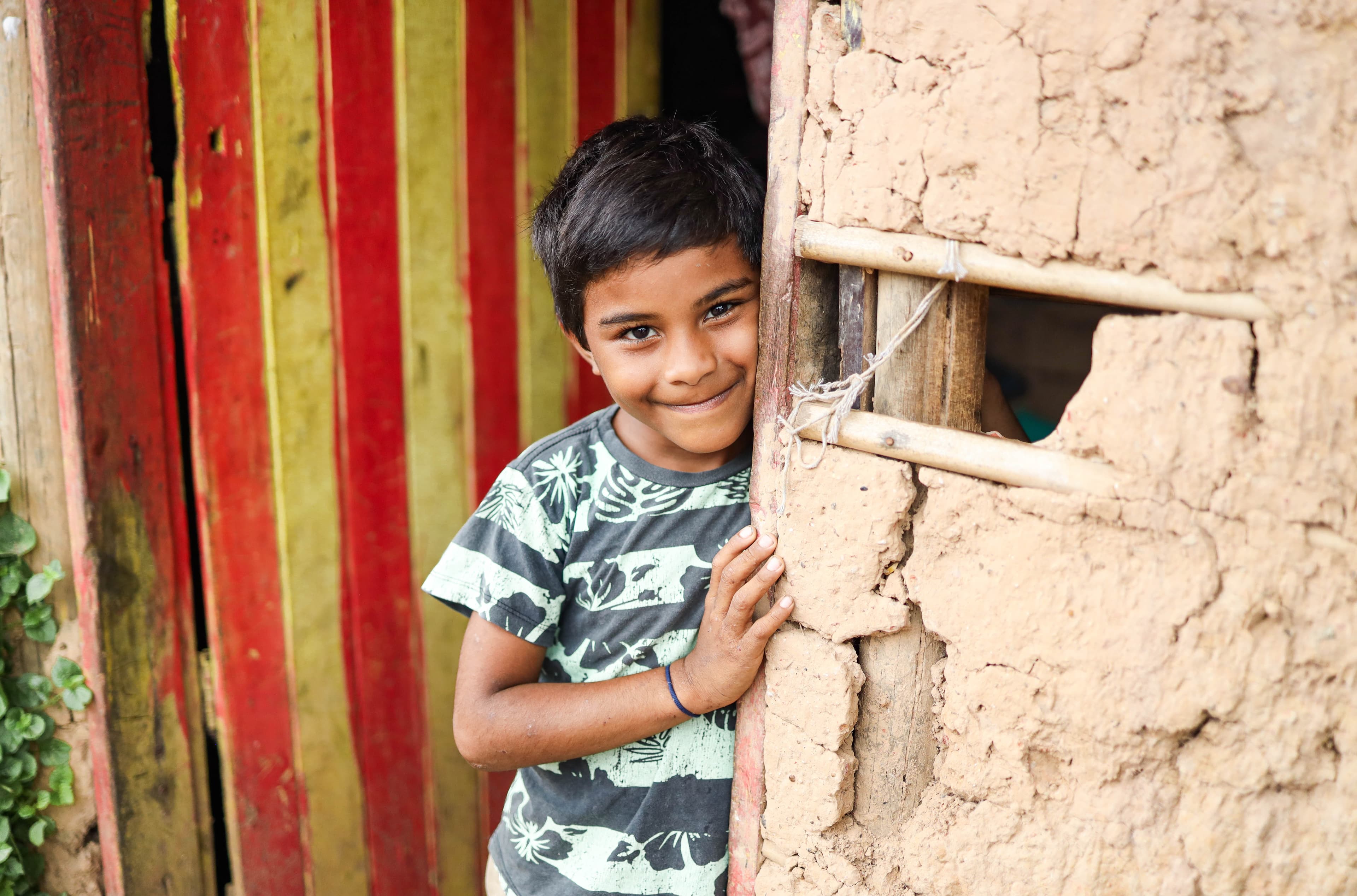 Young boy standing in a door way smiling.