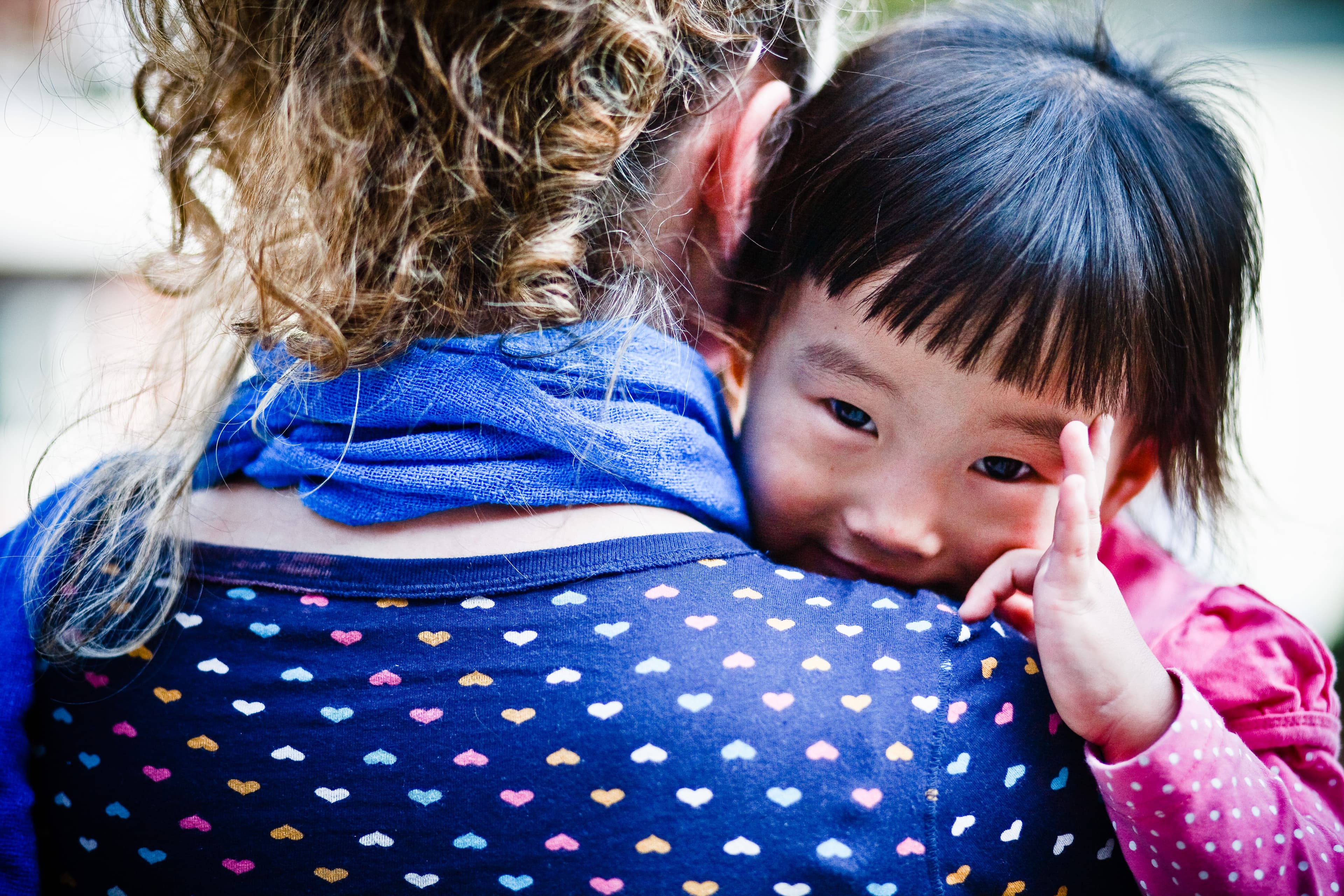 A young woman holds a young Korean girl.