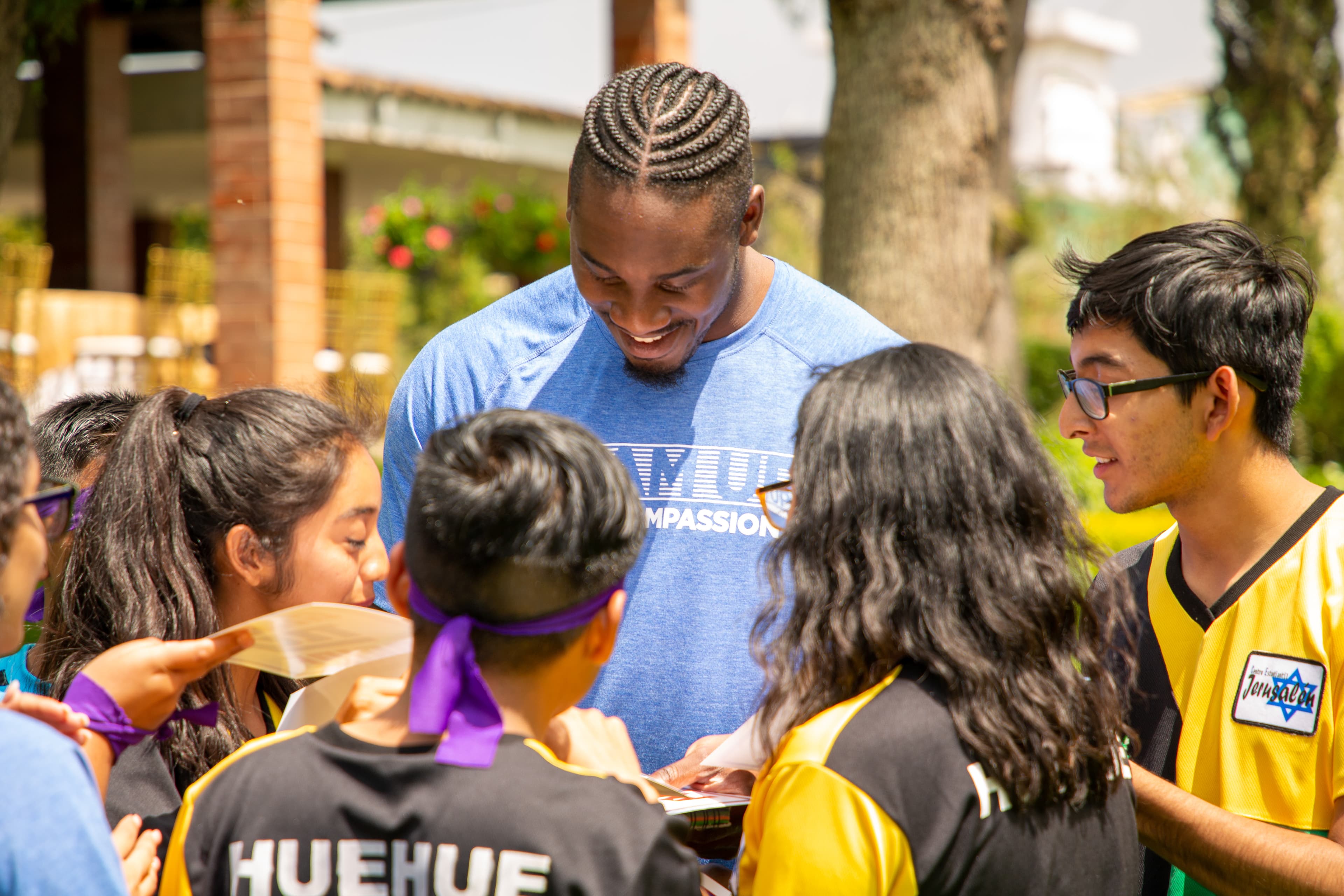 An NFL athlete stands in a circle with children