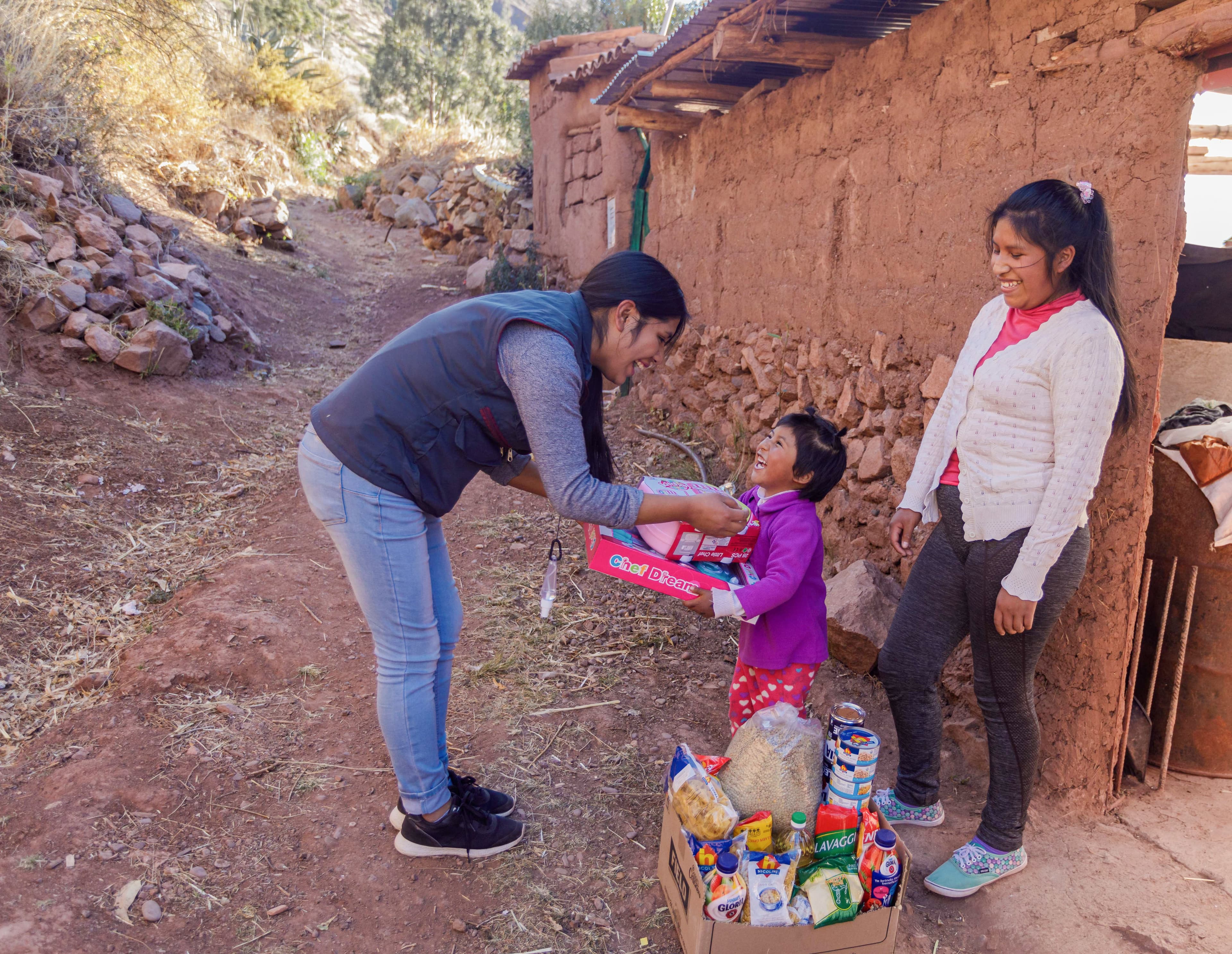 An older woman hands a young child food while they both smile widely.