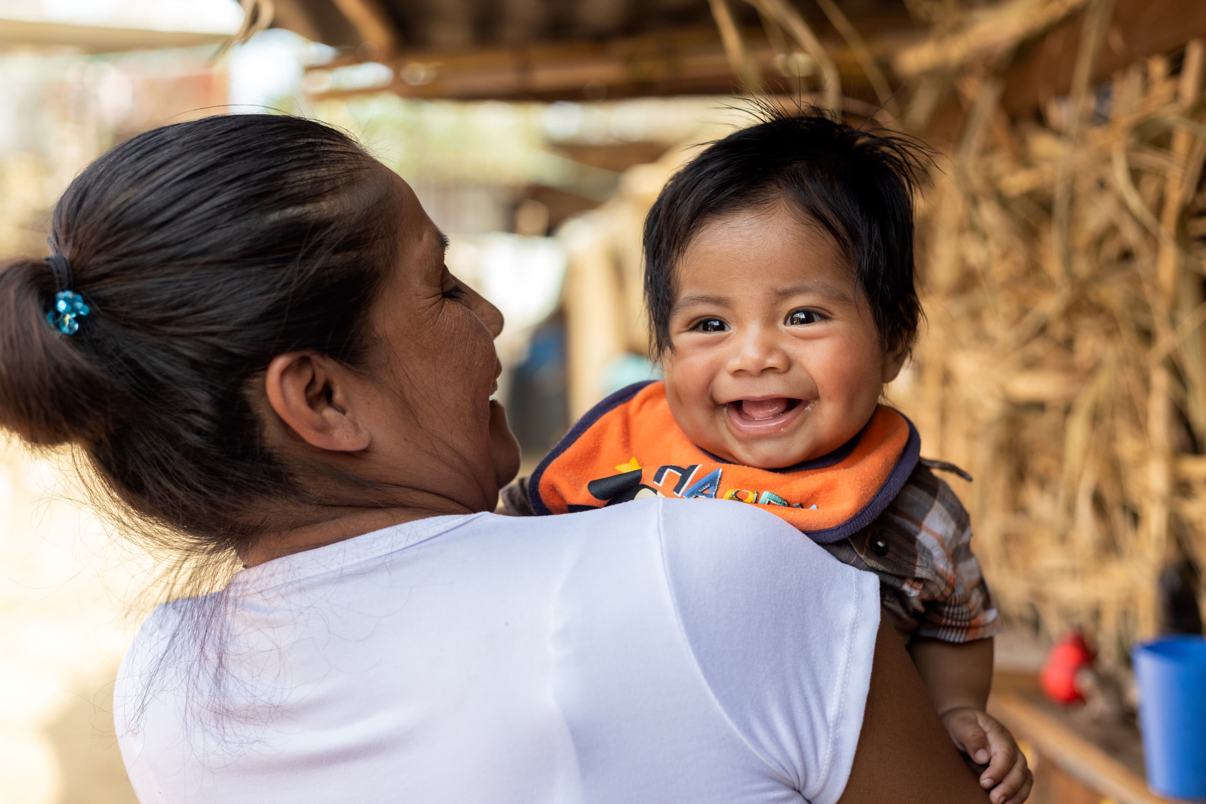 A mother is holding her smiling baby in her arms.