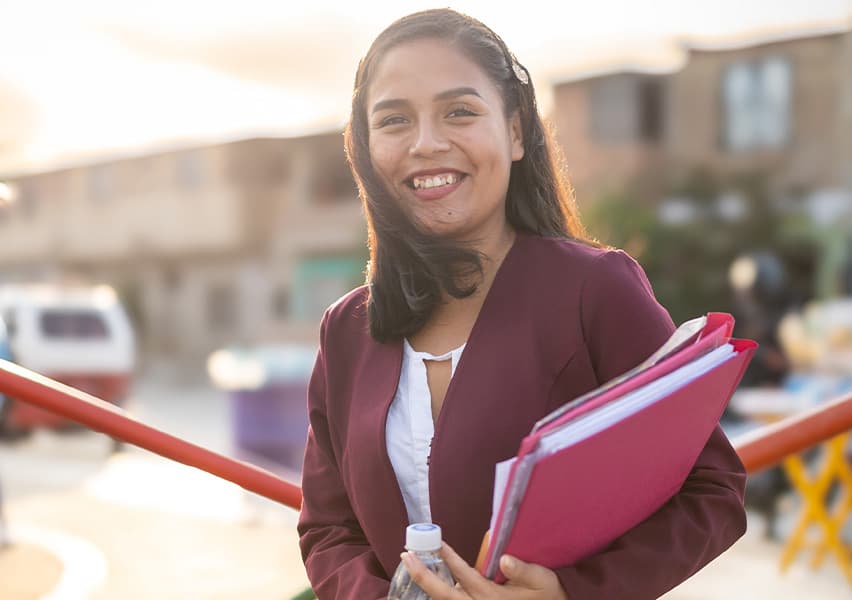 A young boy smiles as he holds a spoon of food