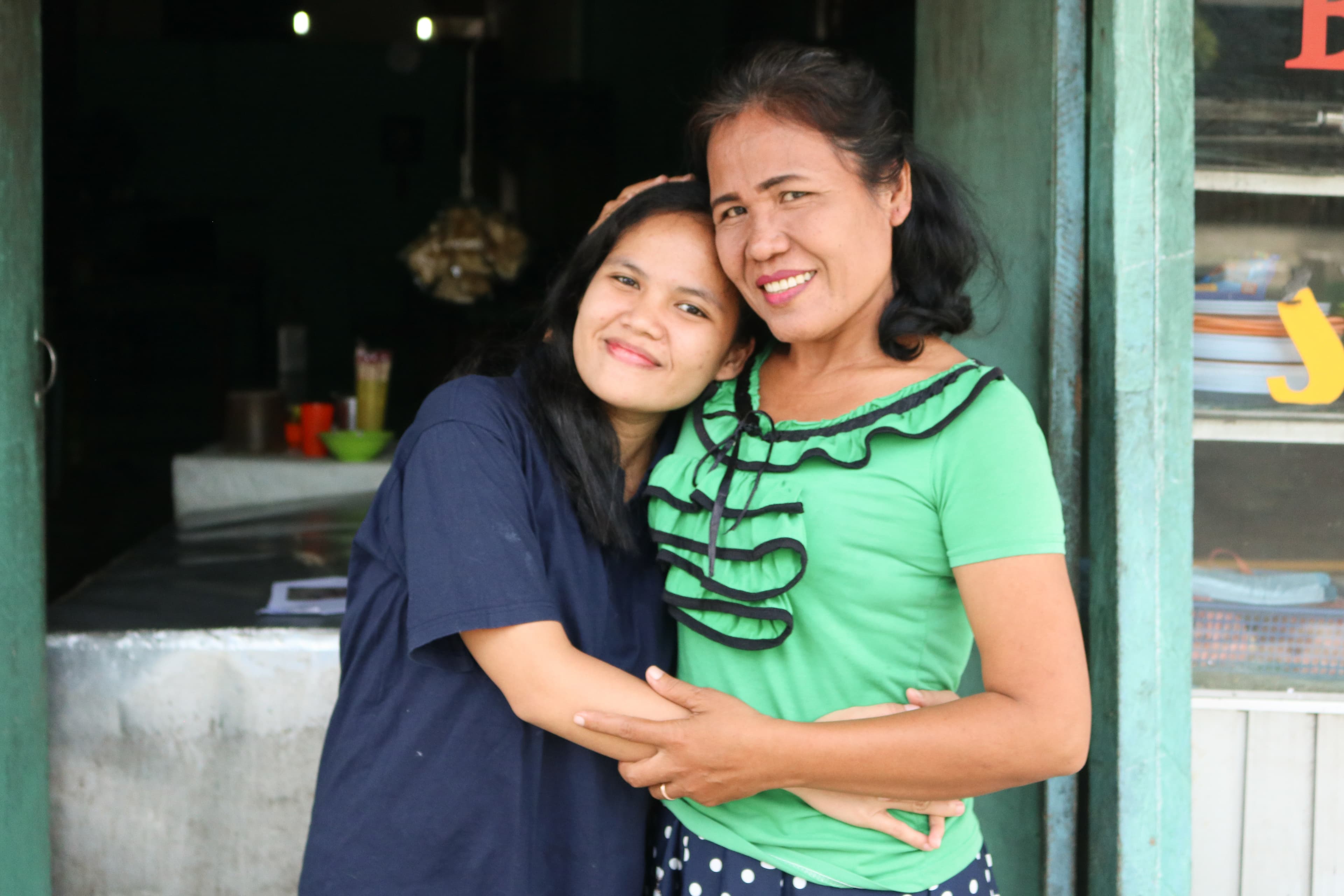 Mother and daughter embrace and smile while looking at the camera