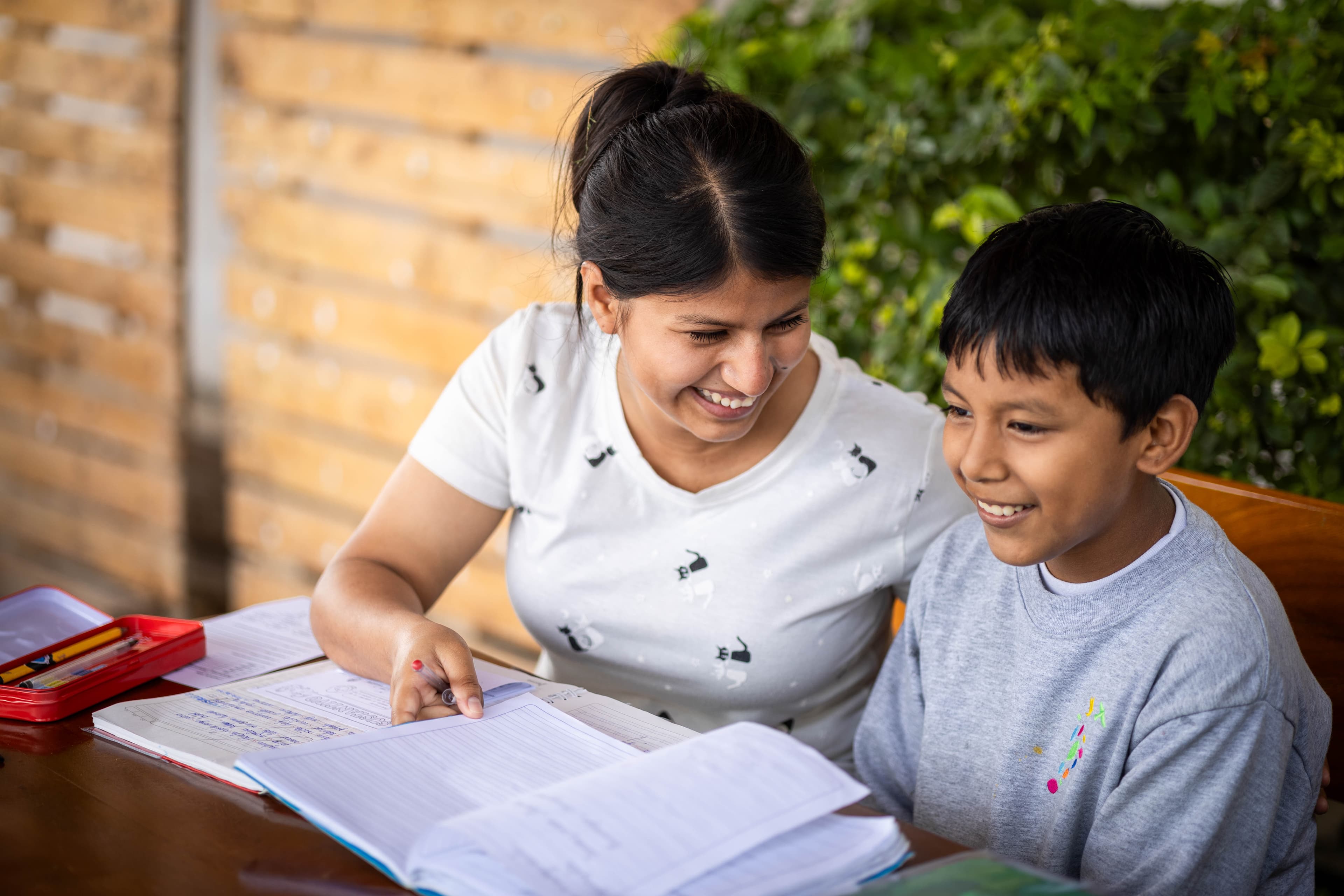 A Center staff member sits outside at the Compassion project, helping a child with his homework.