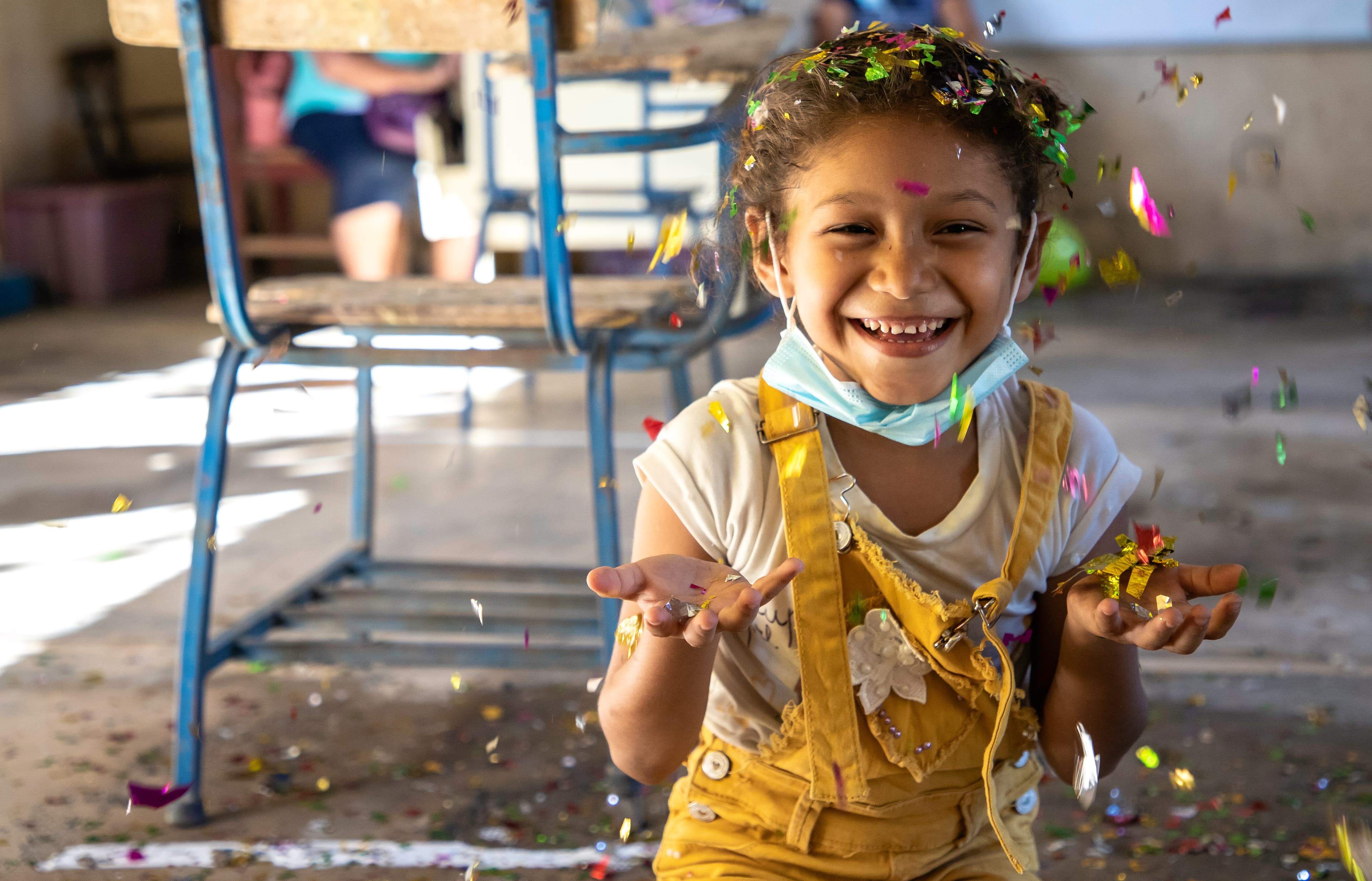 Young girl is smiling and playing with falling confetti.
