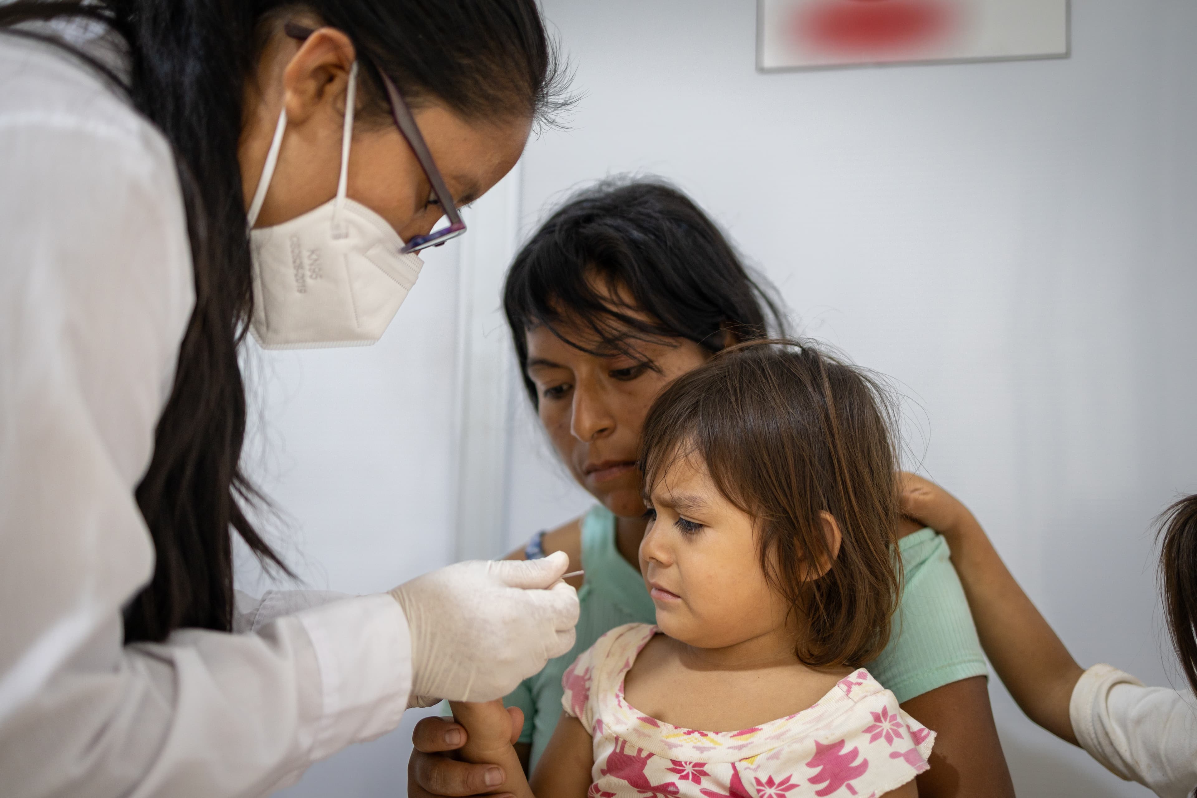A young girl looks a sample being held by a female doctor.