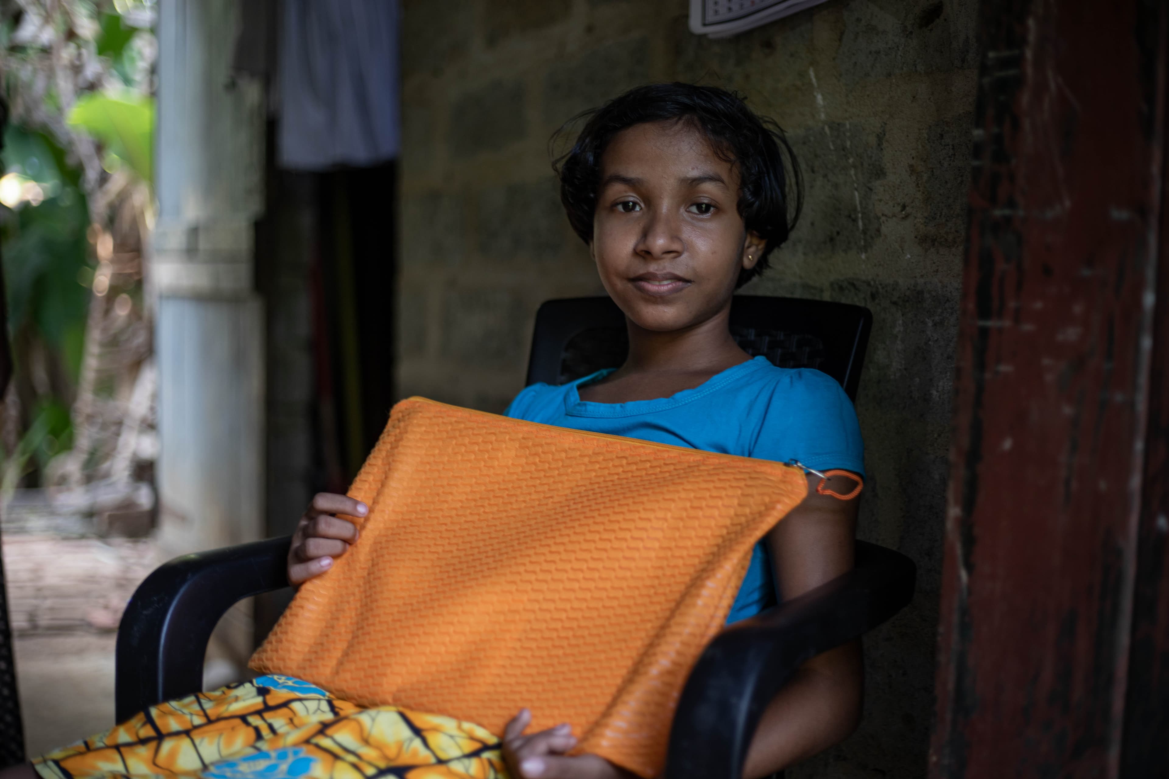 A young girl is sitting and holding an orange case from her sponsor.