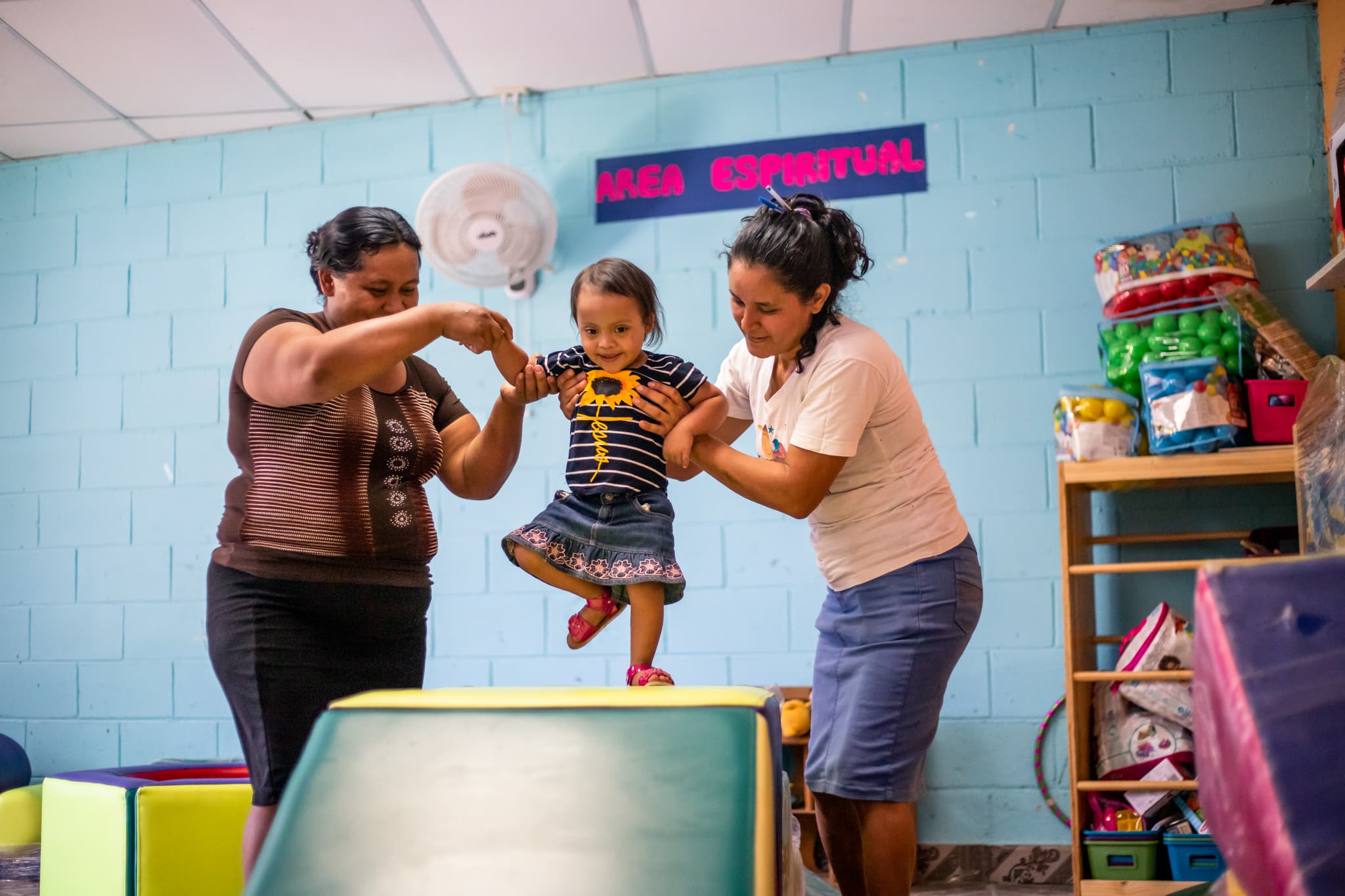 Melany's Miraculous StepsTwo women hold a toddler girl up as she walks.