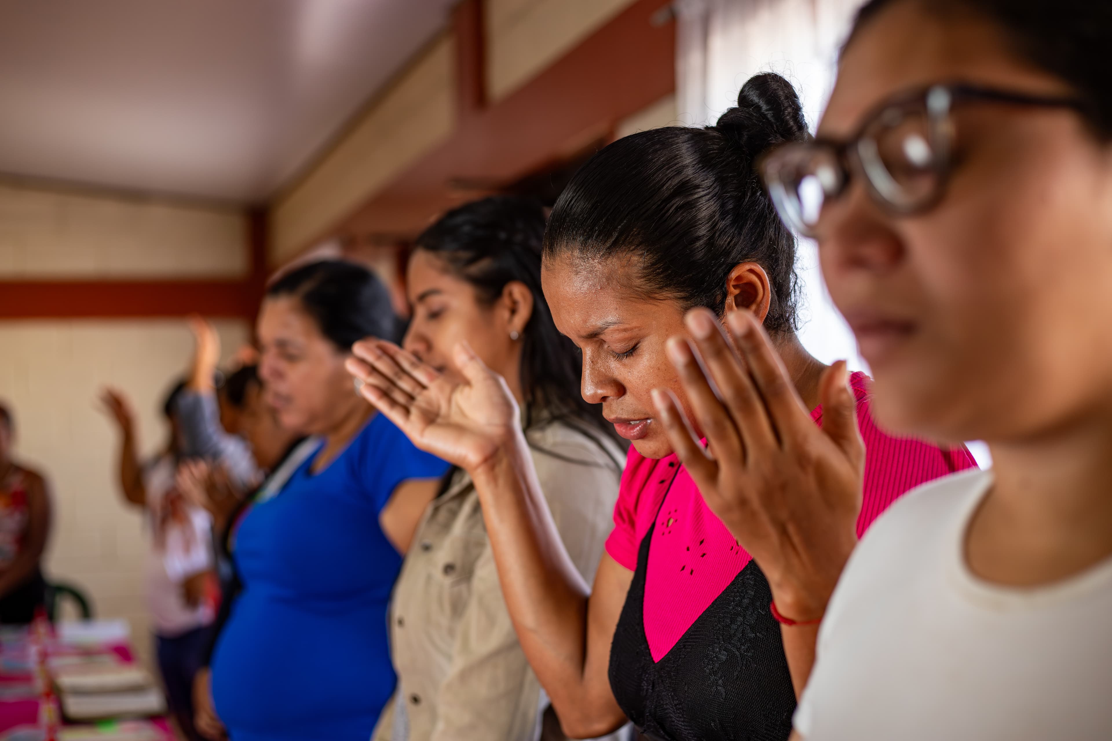 A group of women sing and praise with their eyes closed.