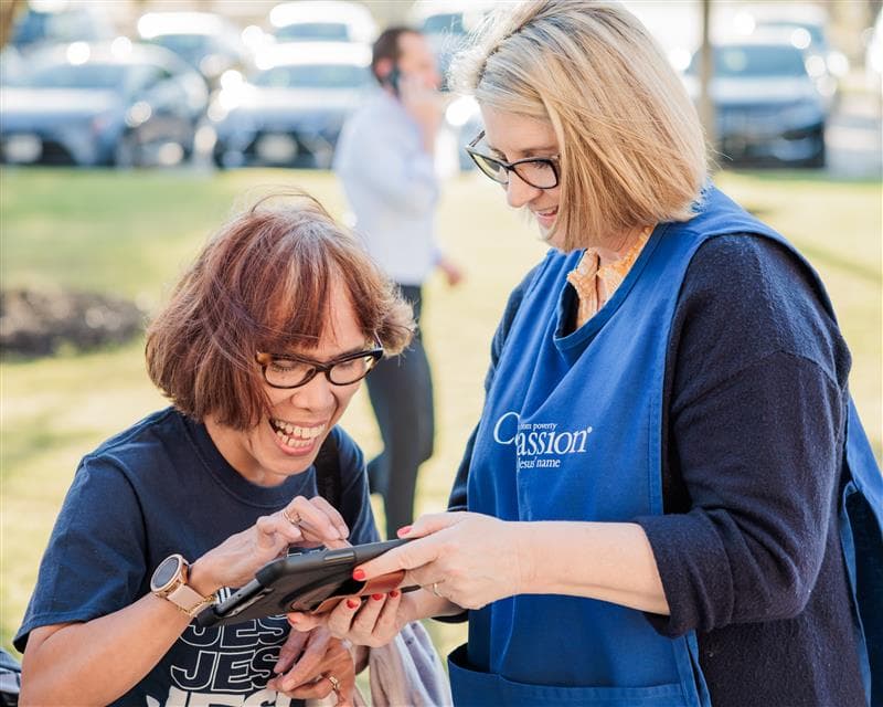 A woman is excitedly tapping a tablet screen during a Compassion live event.