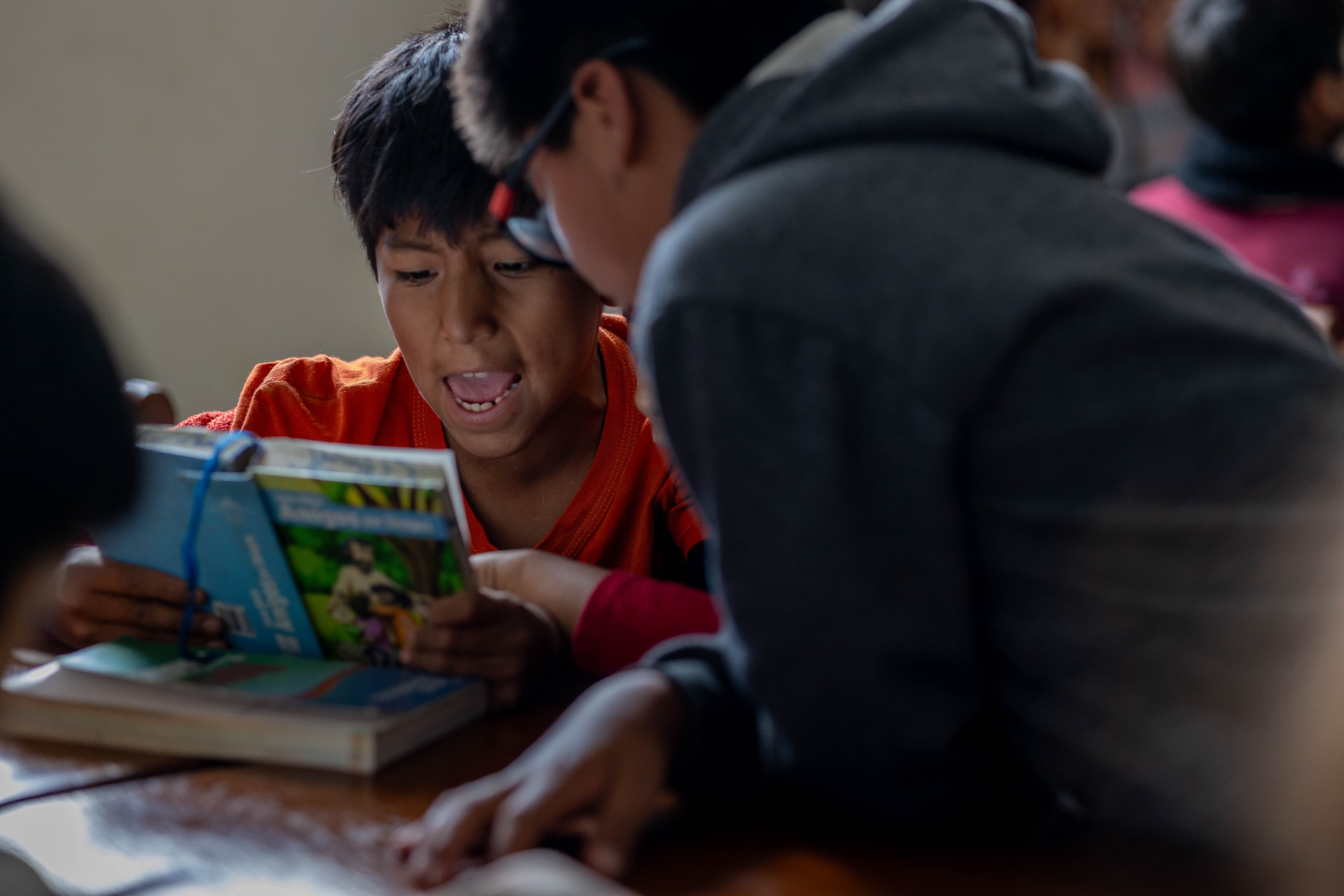 Two boys excitedly read a Bible together in their classroom at the center.