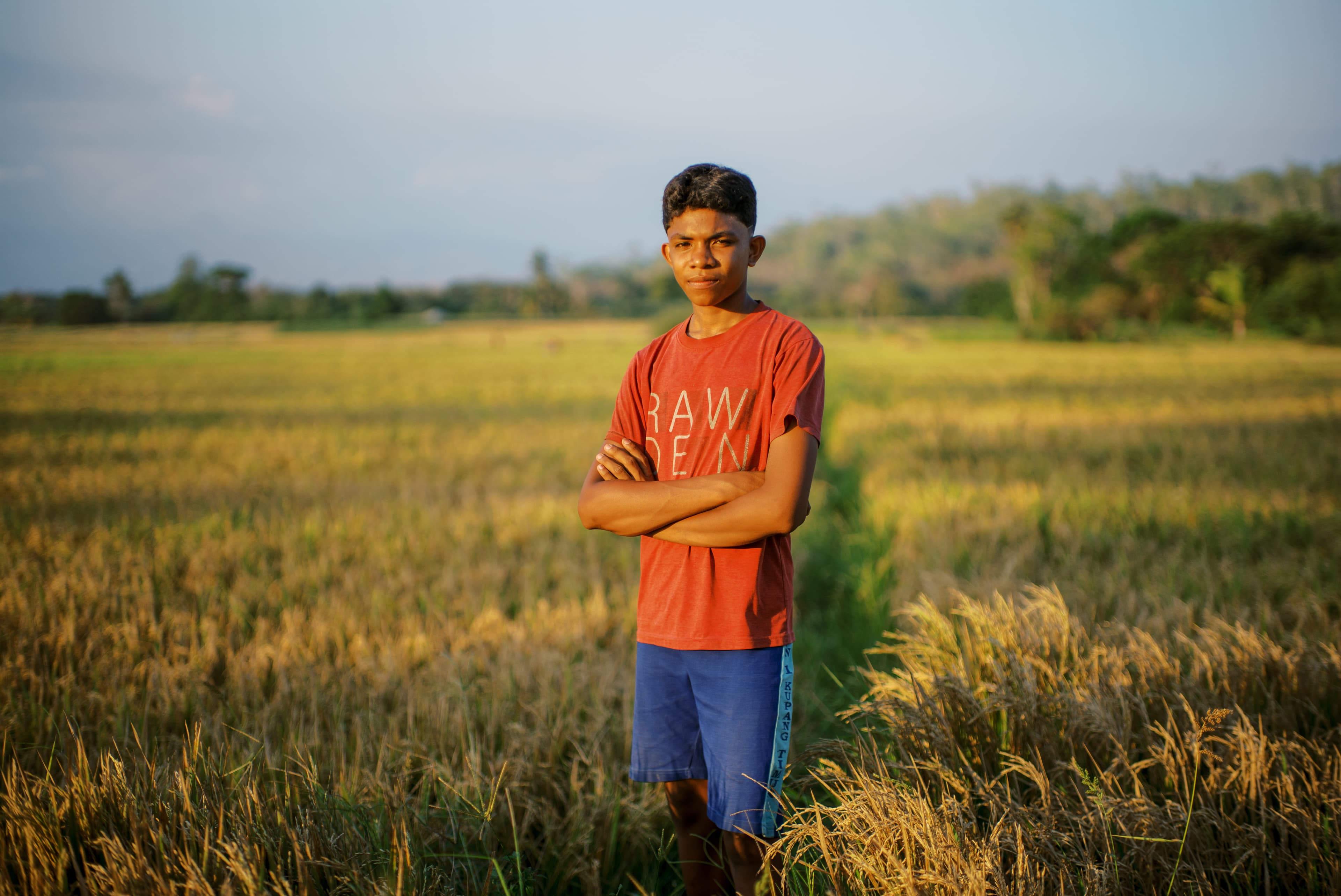 A young man is standing in a rice field.