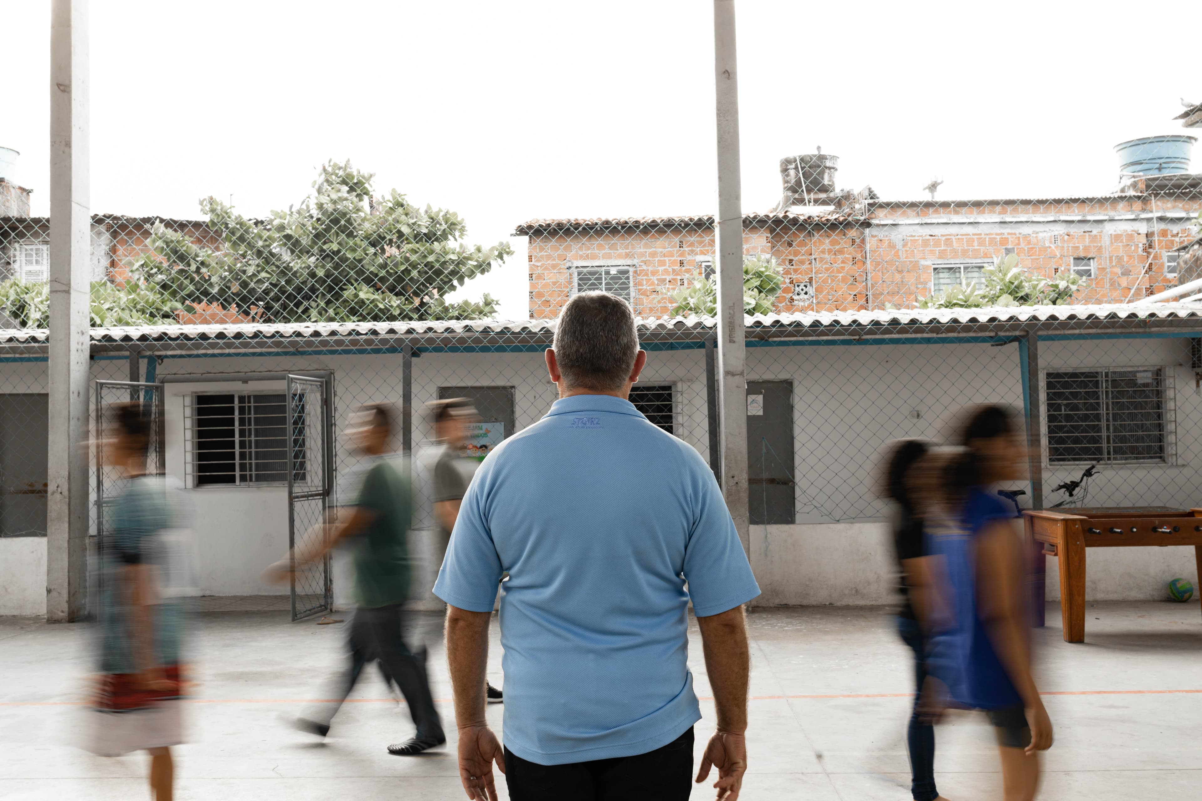 An older man wearing a blue shirt stands with his back to the camera.