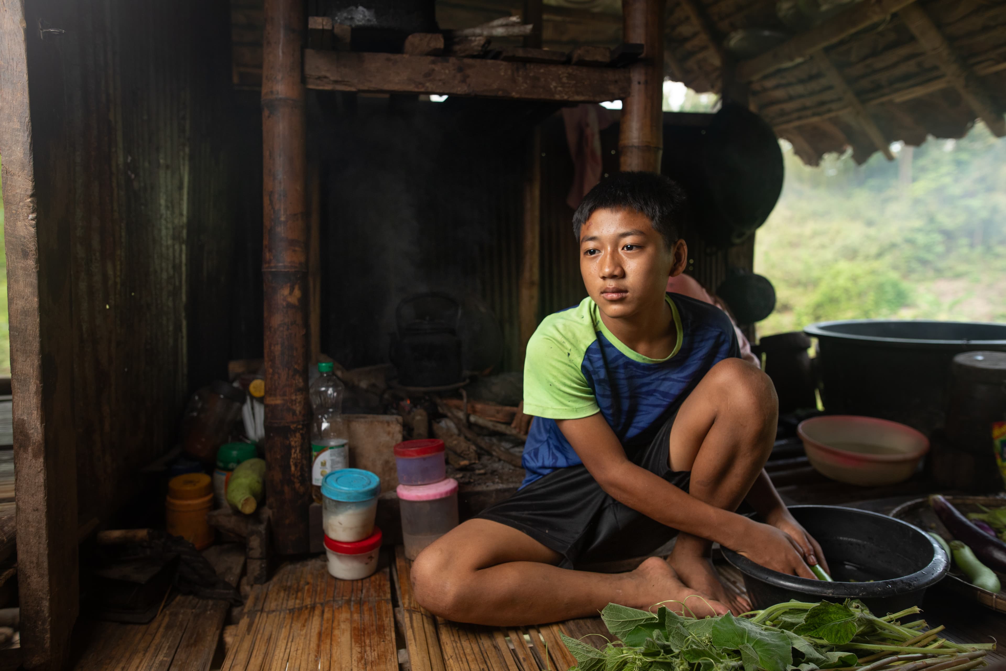 A young man is sitting on the floor washing vegetables in his home.