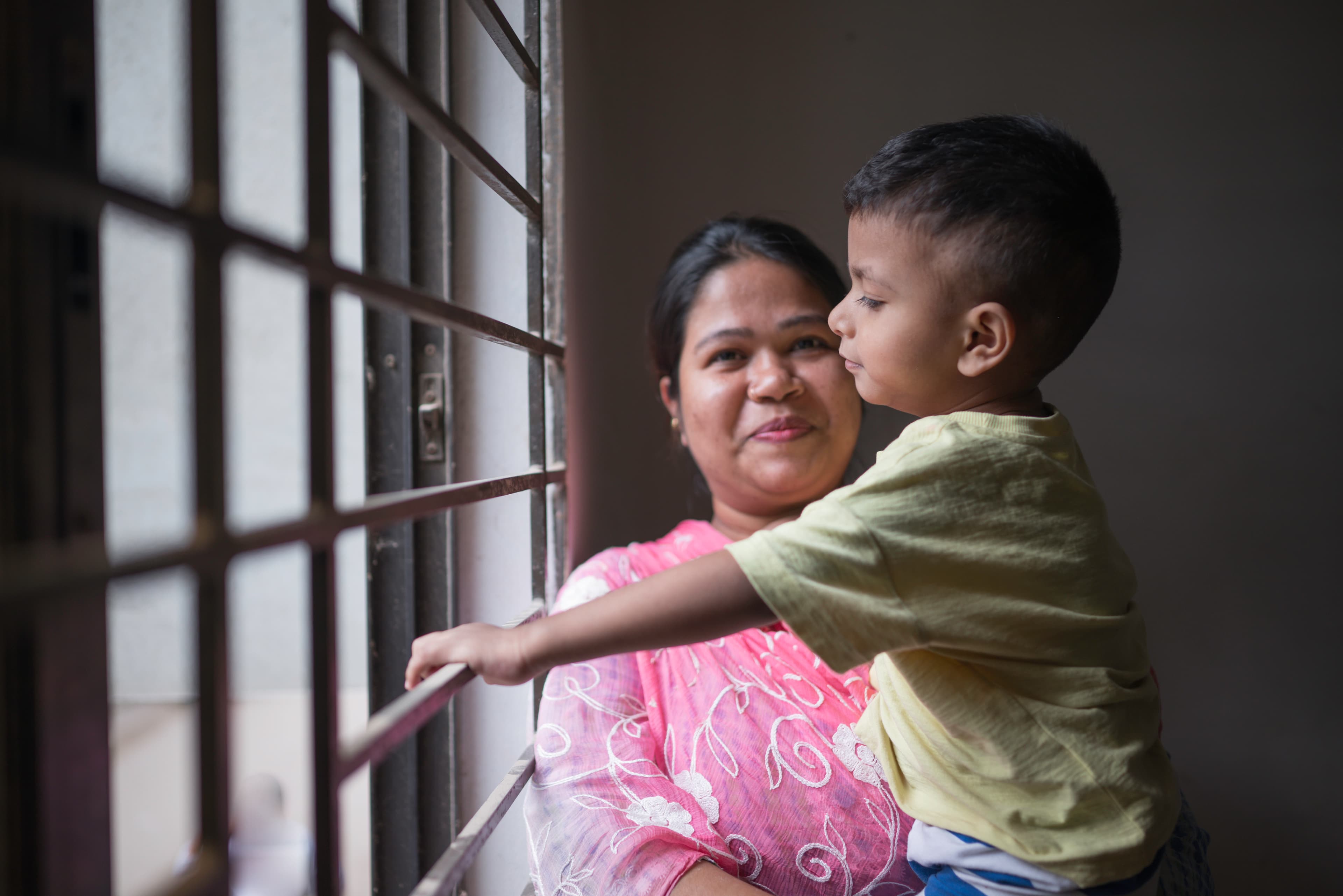 A mother holds her son in her arms while smiling.