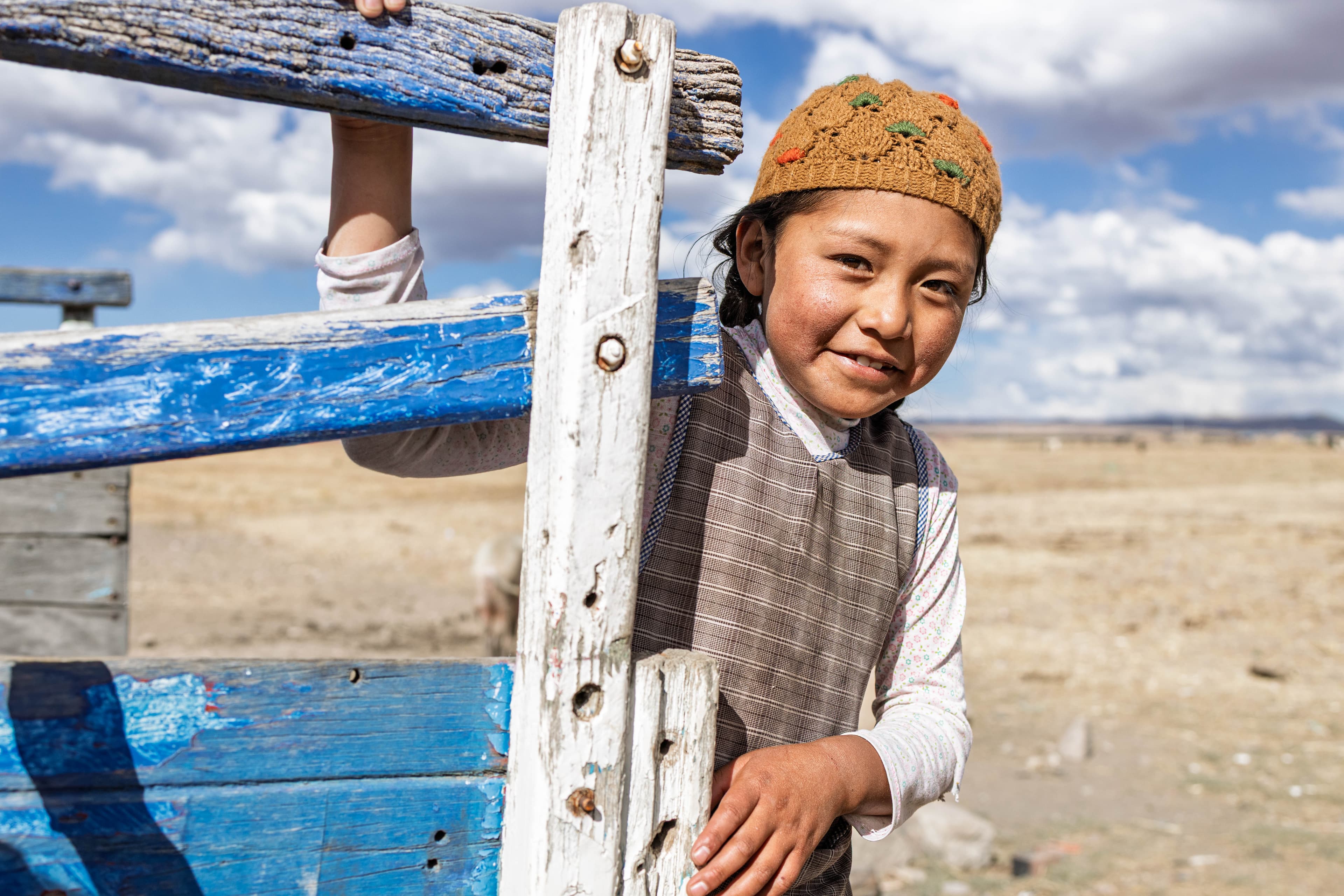 A young child is holding onto the back of a vehicle smiling.
