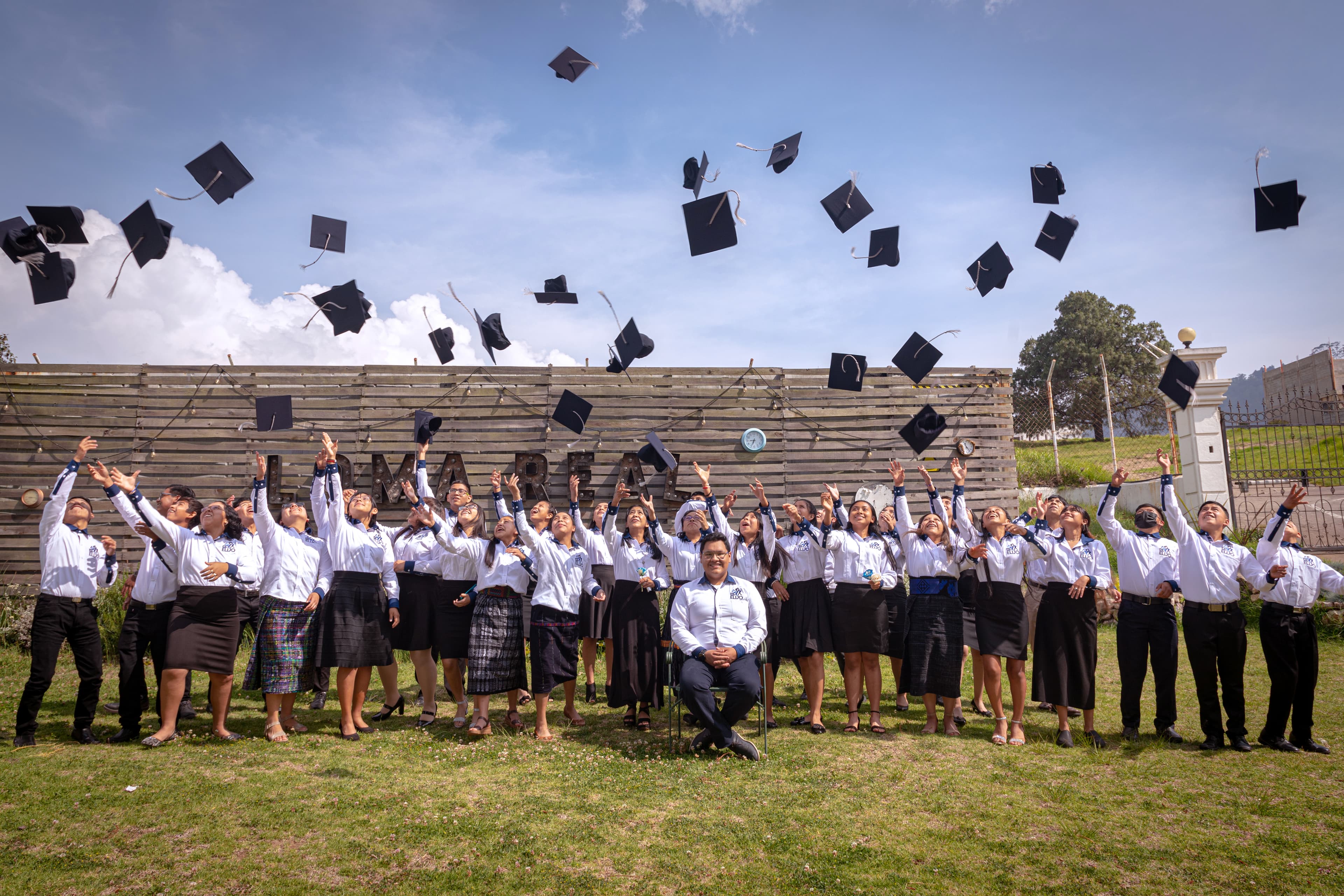 A group of young adults throw their graduation caps into the air.