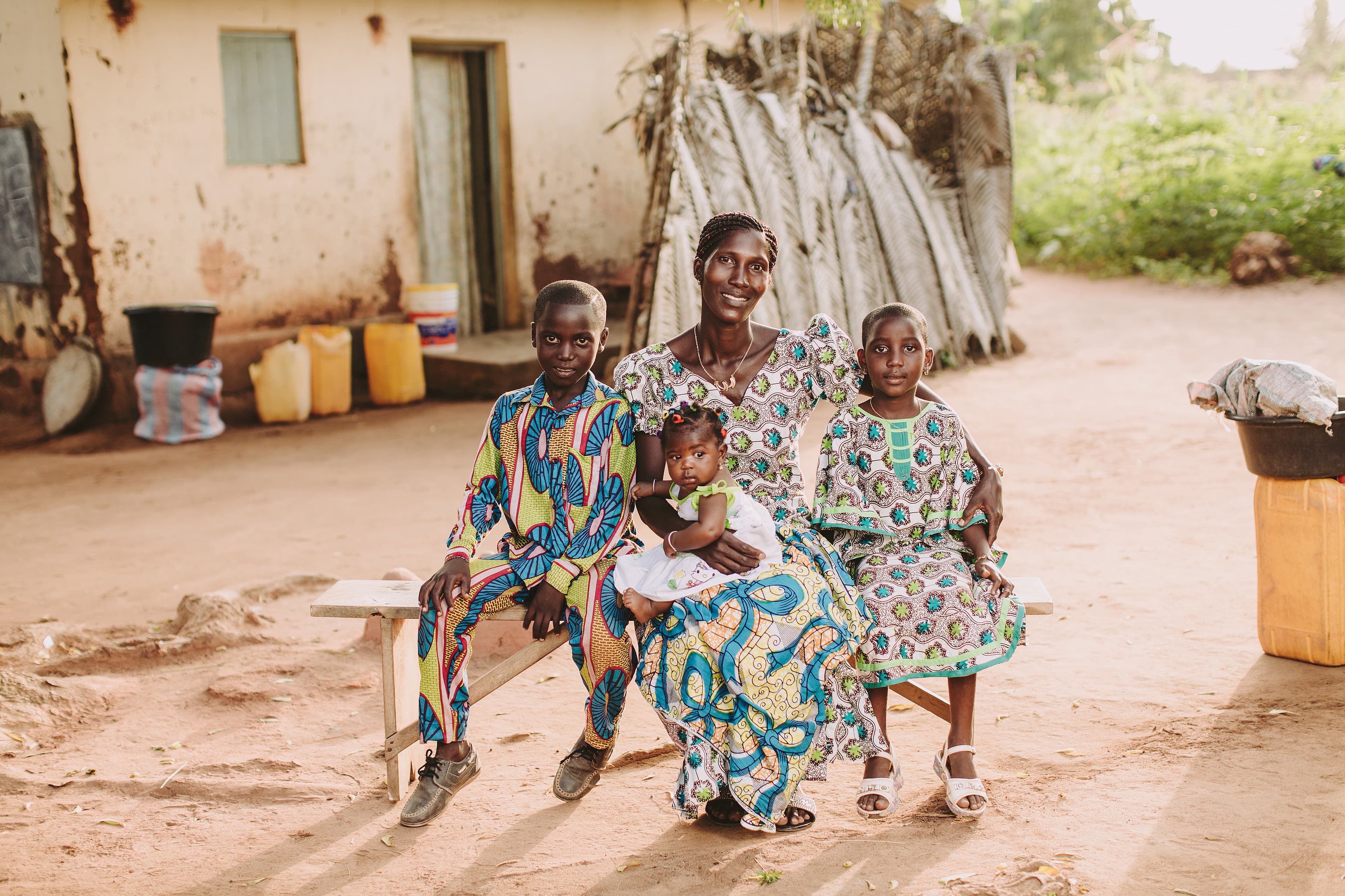 A mother is sitting with her three children on a bench.