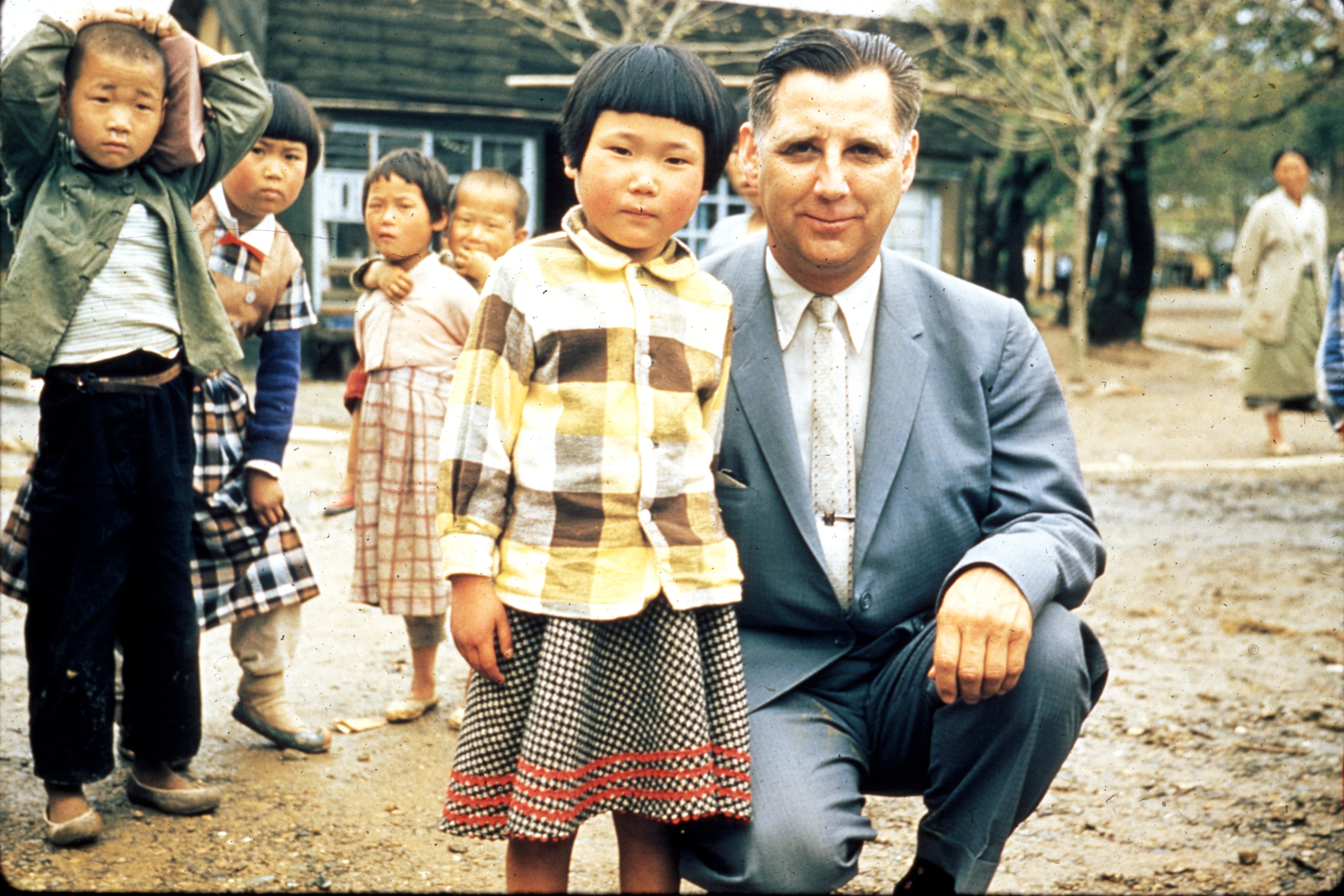 Everett Swanson is kneeling down standing next to a small young girl.