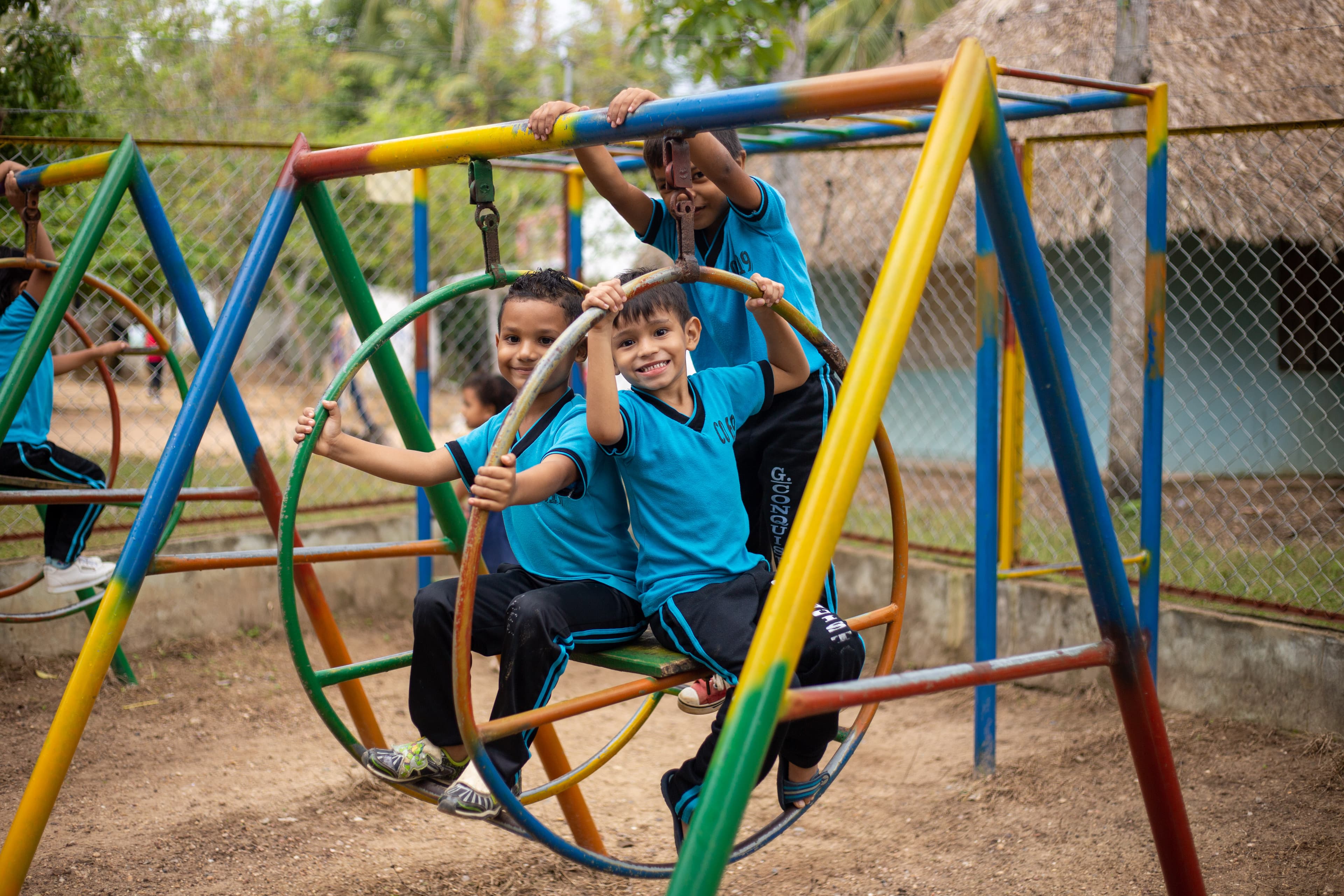 Three boys in blue and black uniforms play outdoors on a playground.