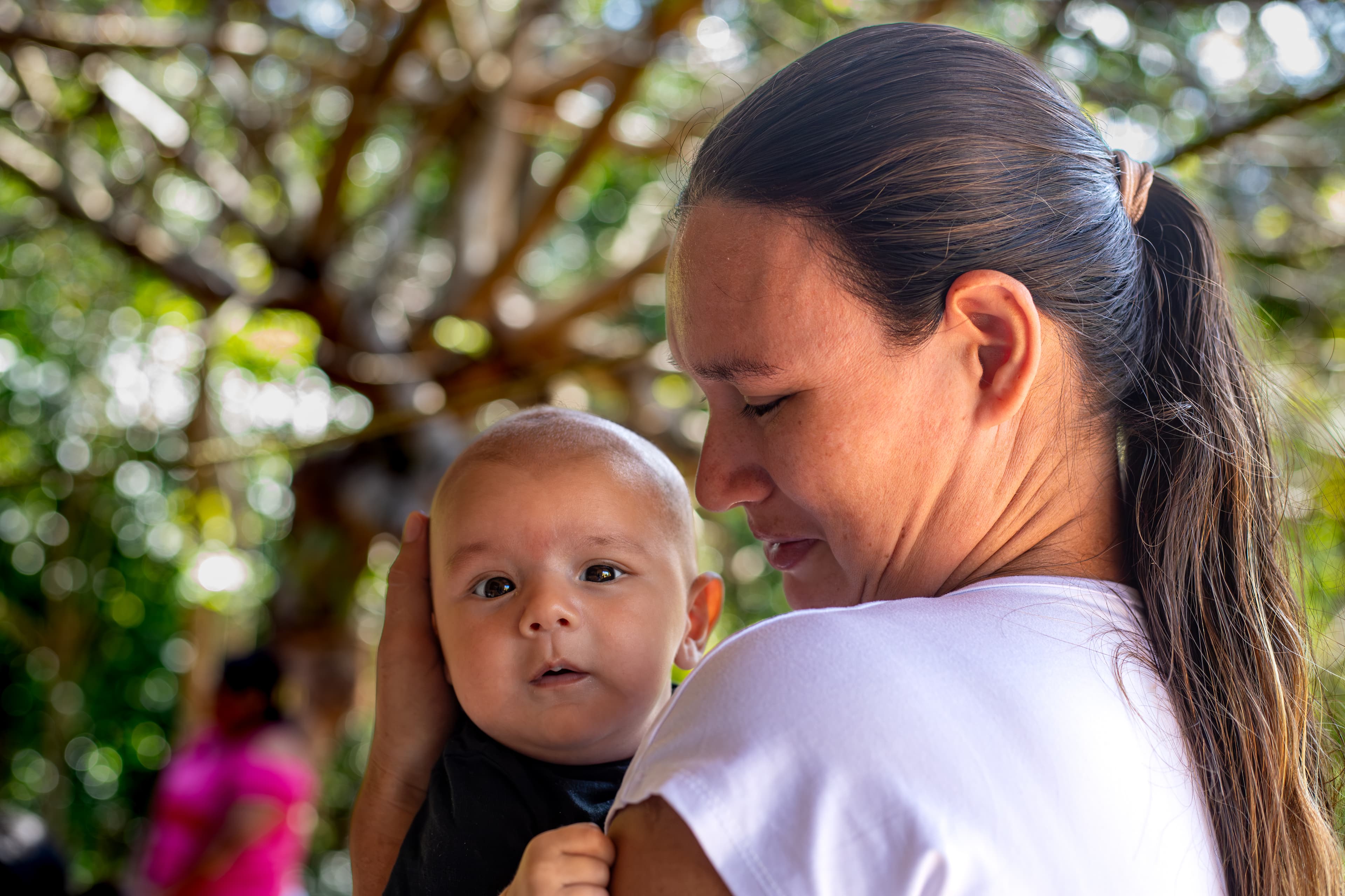 A mom holds her infant son who’s looking at the camera.