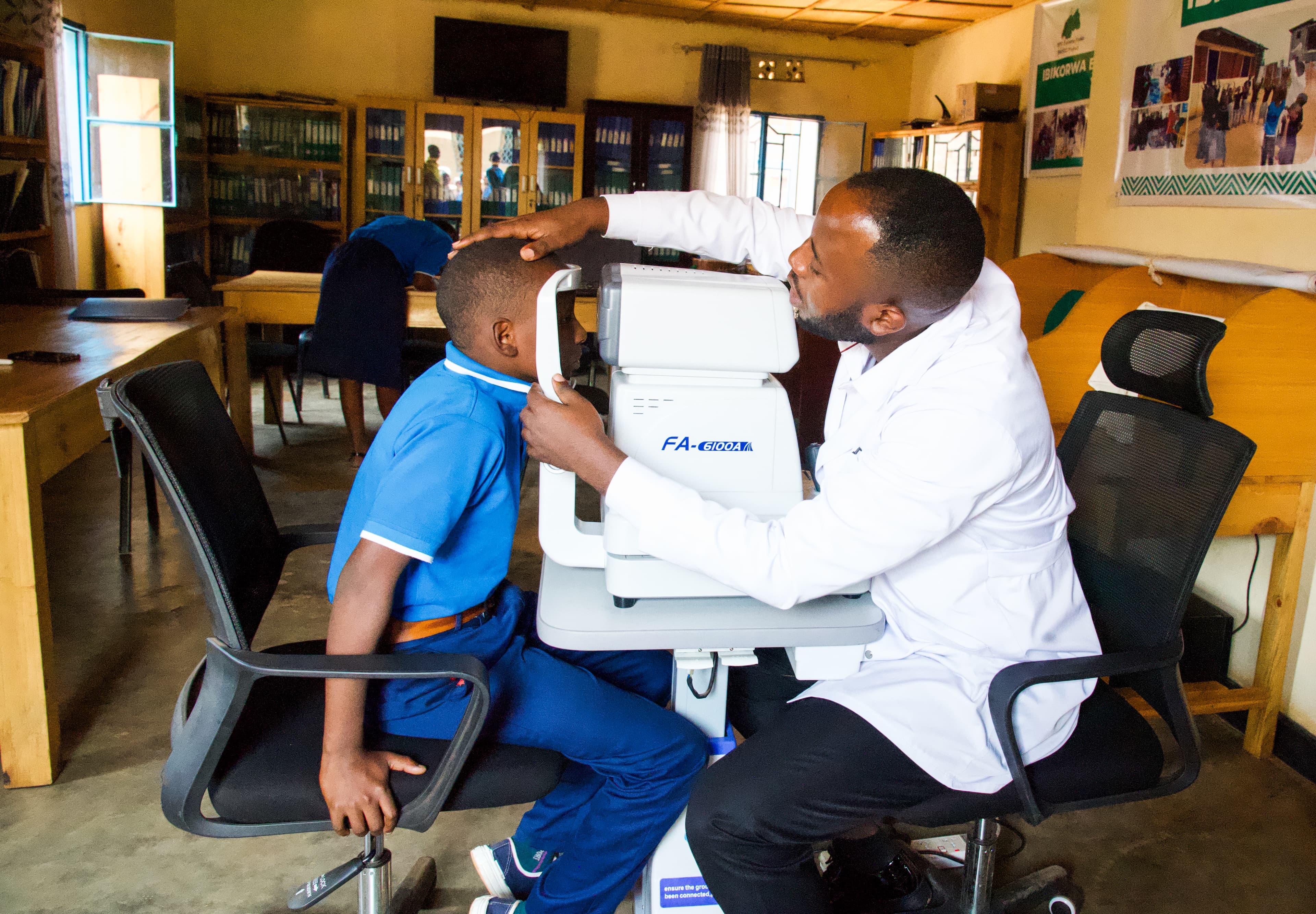 An eye doctor helps an African boy place his head in a device used to check vision.