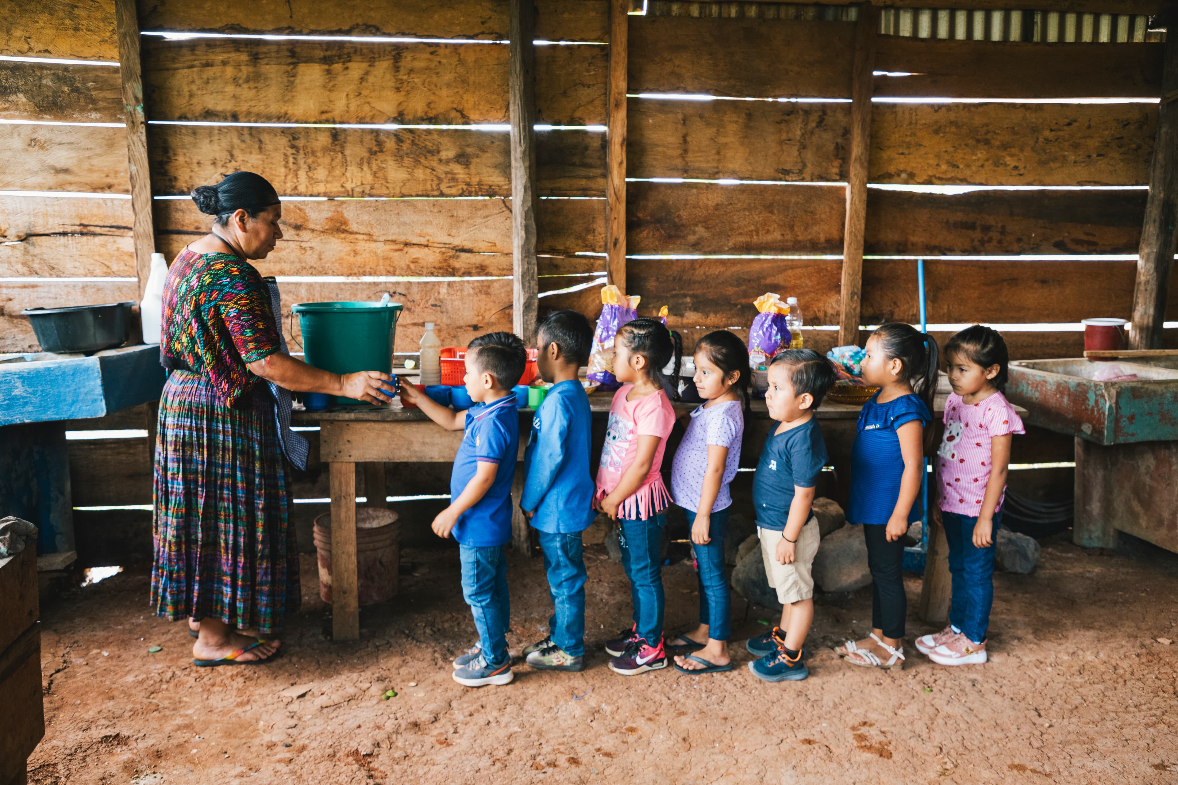 A group of students stand in line to receive a healthy lunch at their Compassion center.