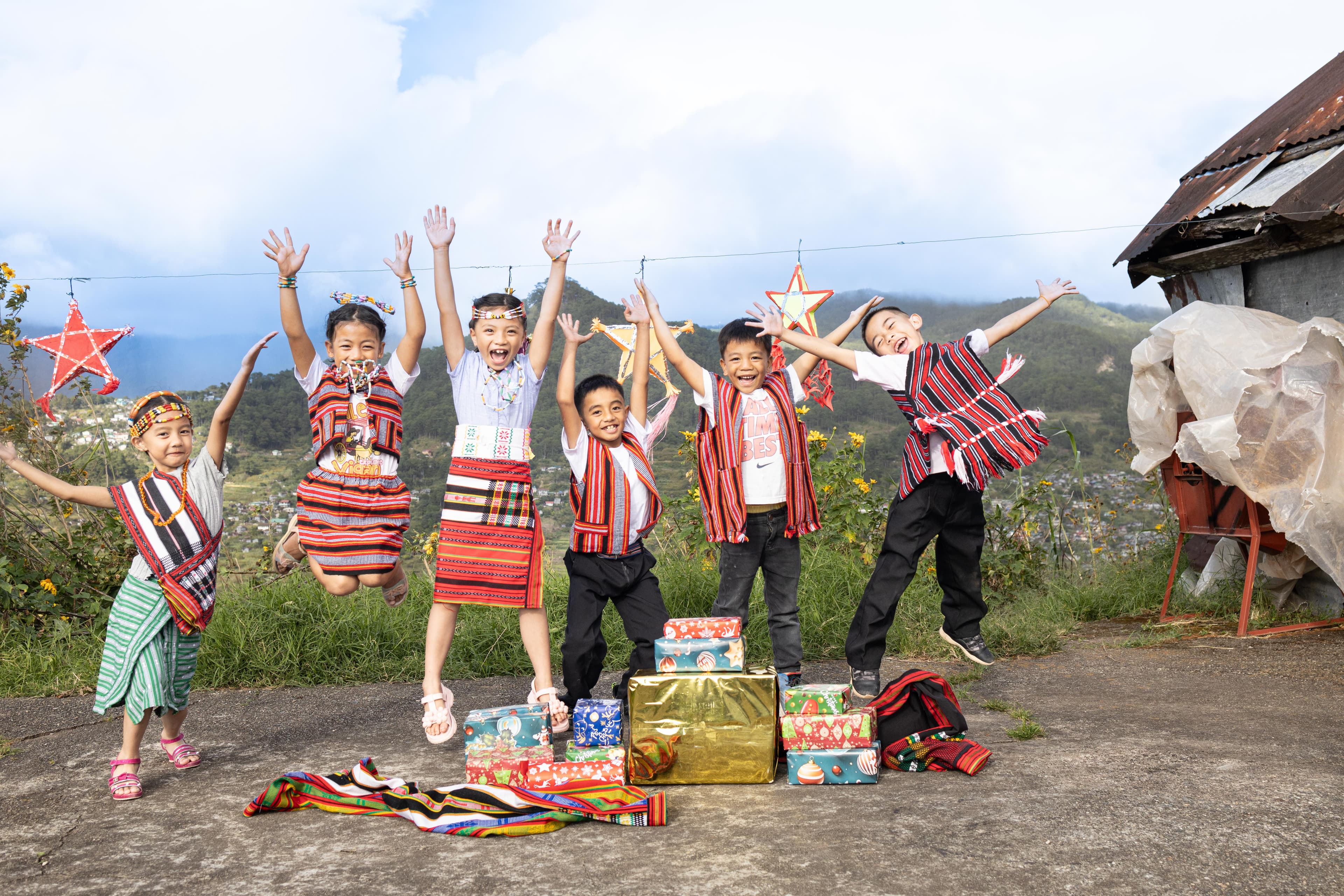 A group of children jump into the air with their hands over their heads.
