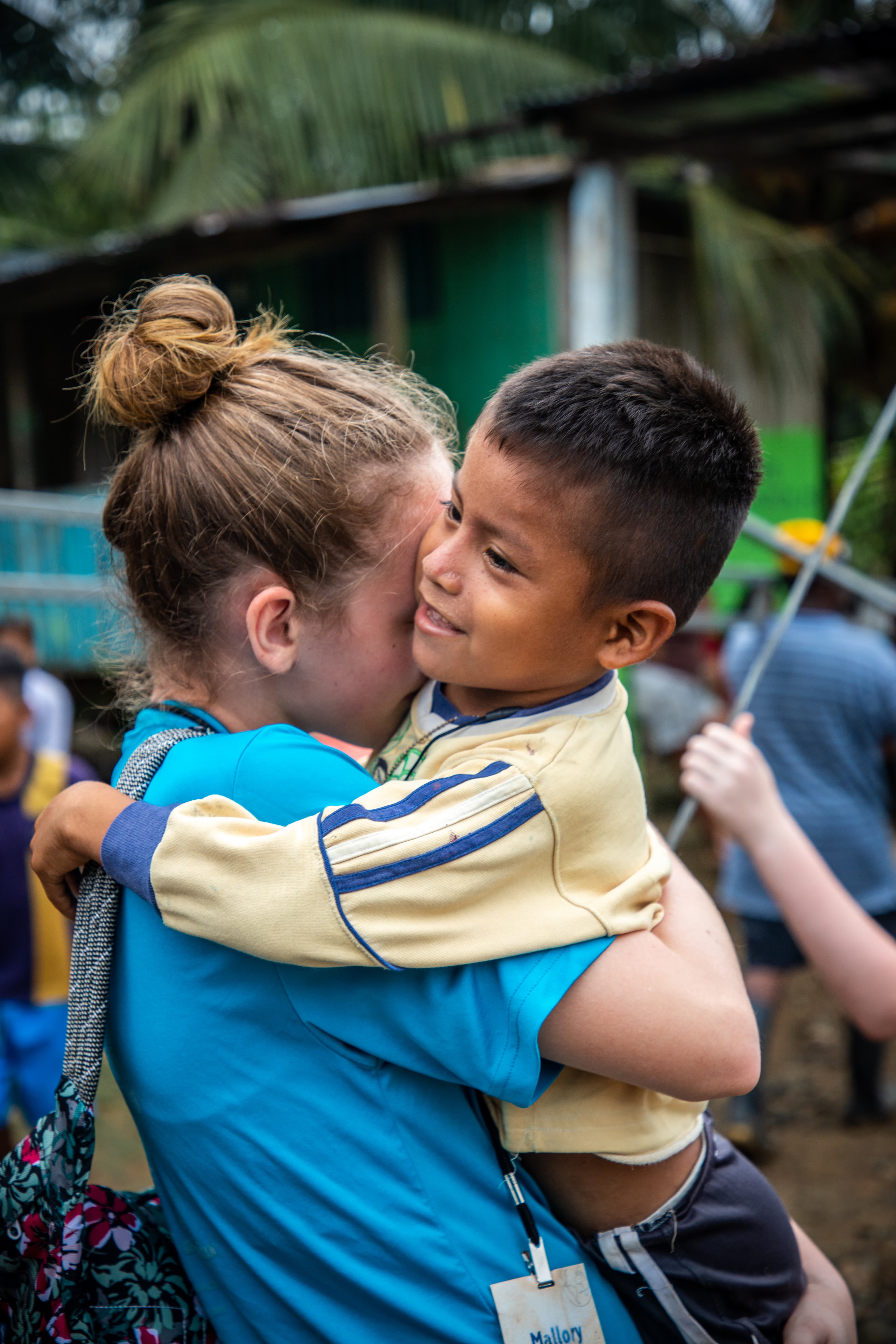 Young woman is holding a small boy and hugging him.