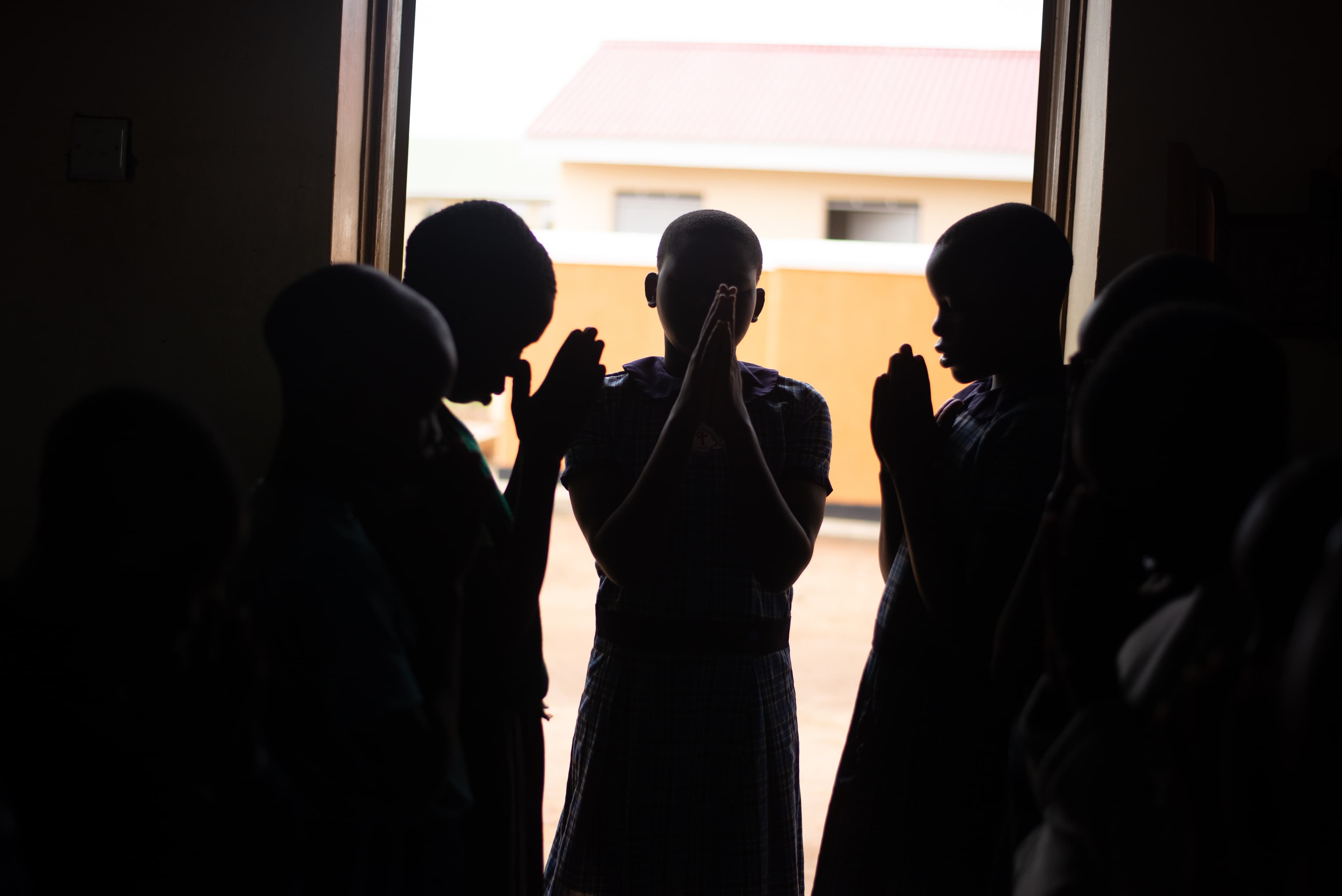 A silhouette of children praying in a hallway.