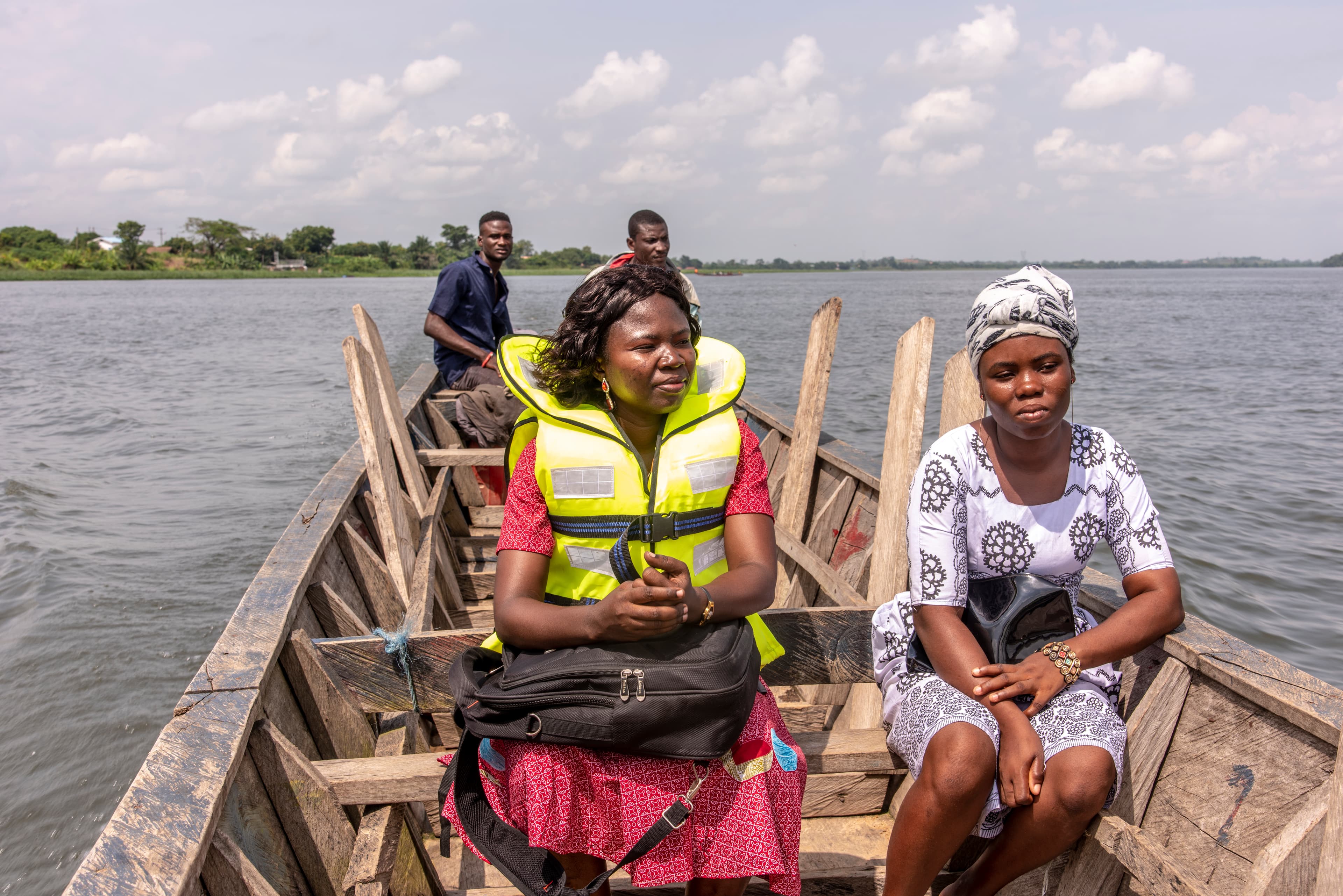 A female social worker is sitting on a boat with a briefcase holding child letters for delivery.
