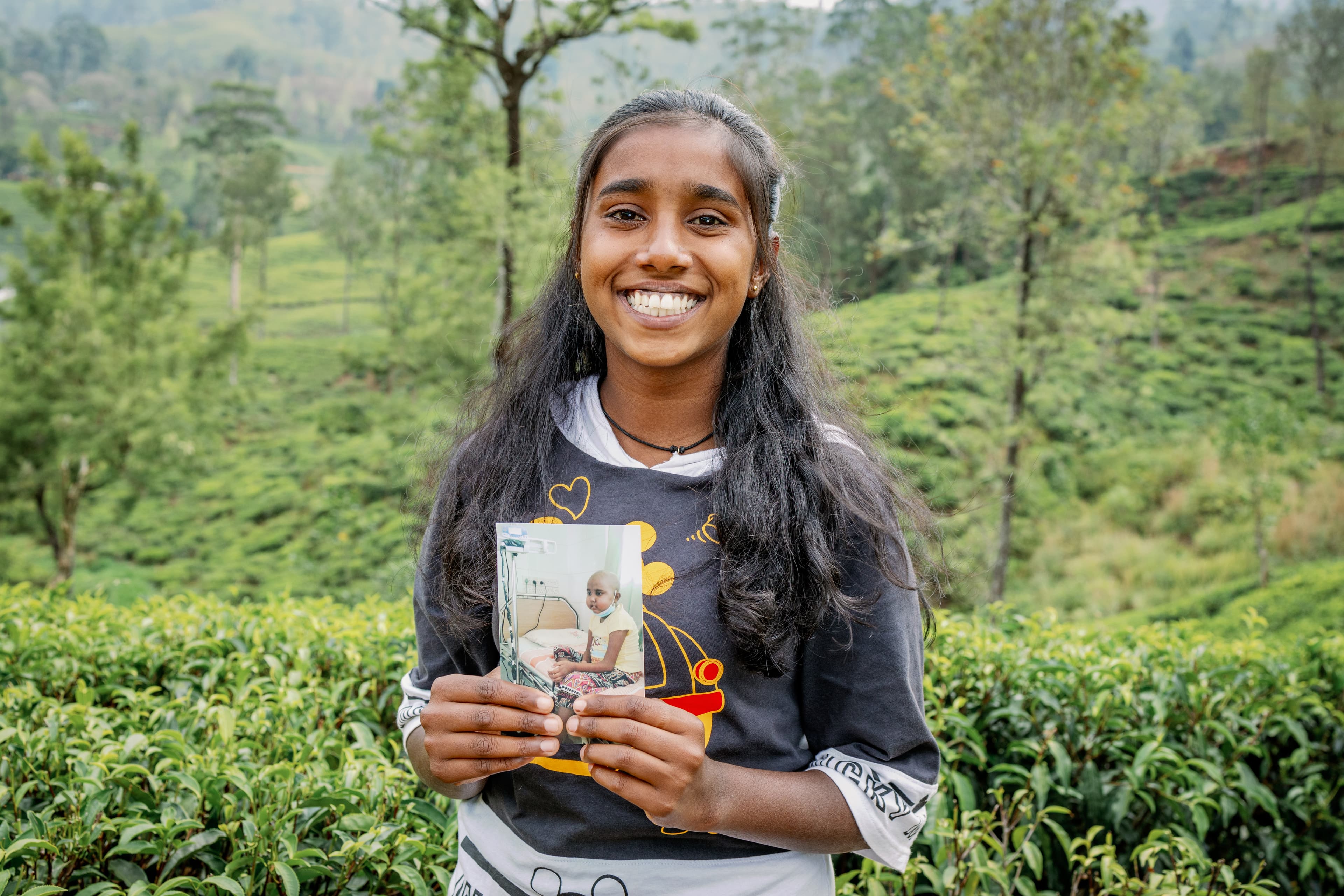A young woman is holding a picture of when she was in the hospital for blood cancer.