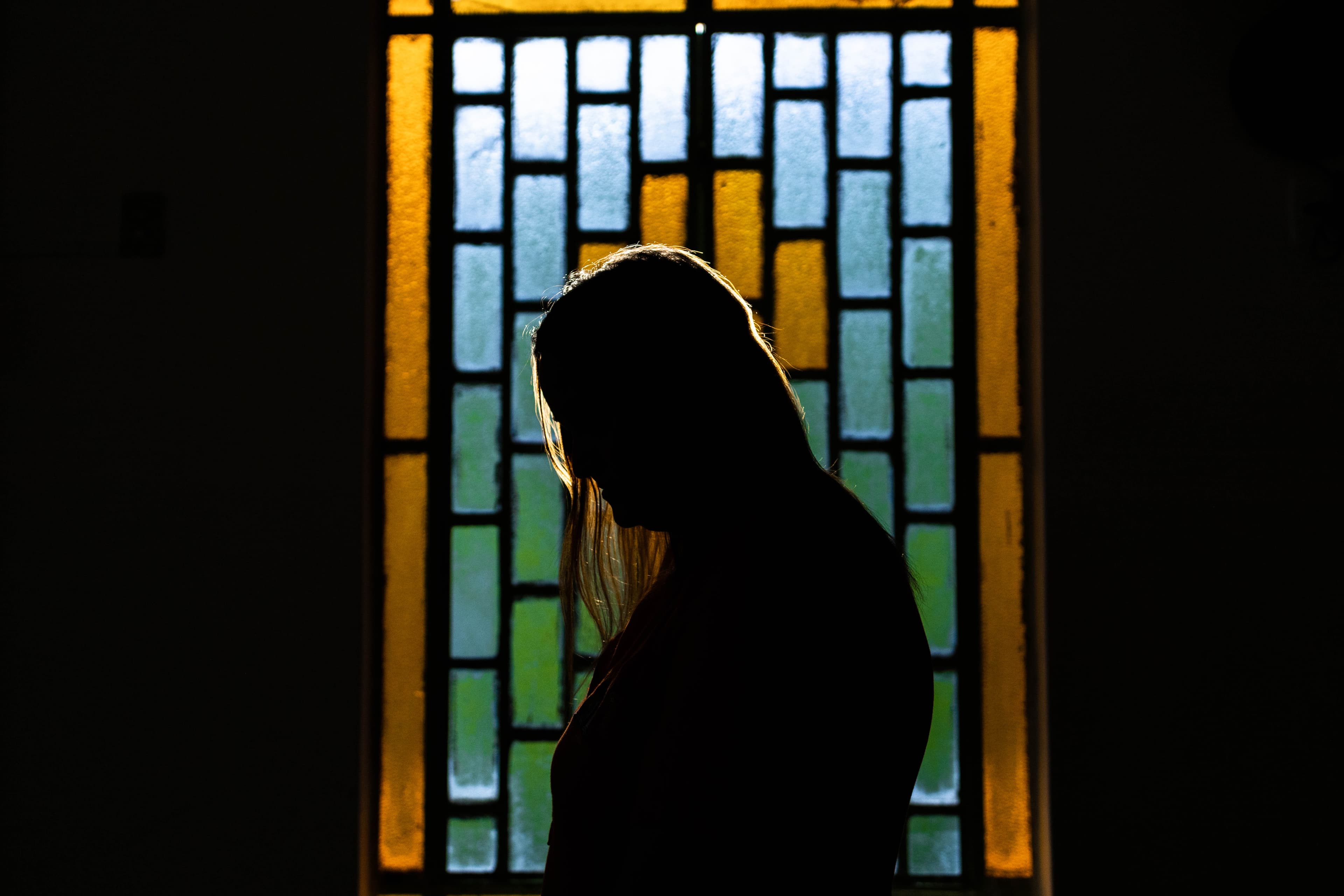 A silhouette of a woman in front of a stained glass window.