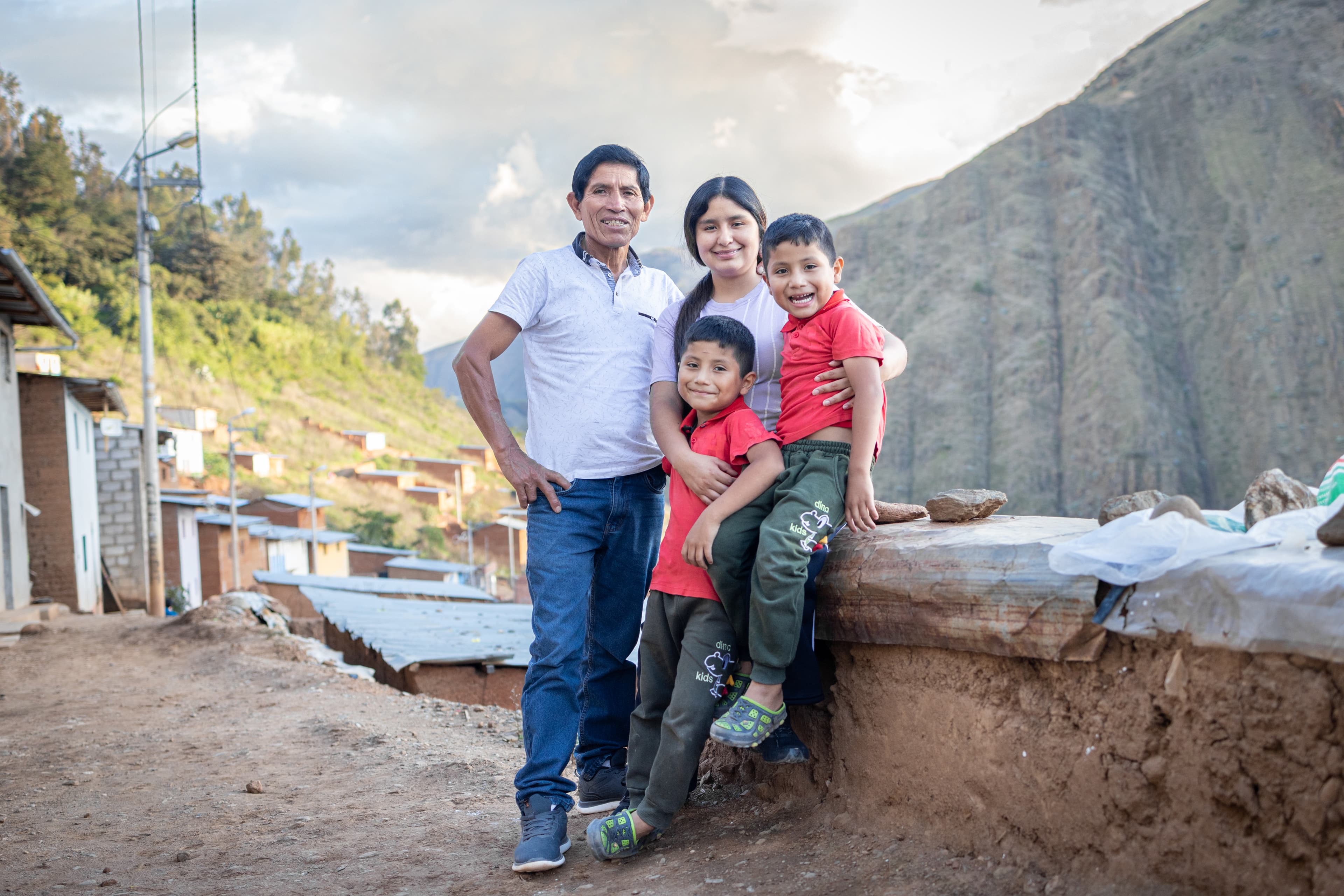 A dad, mom and twin brothers stand together while smiling.