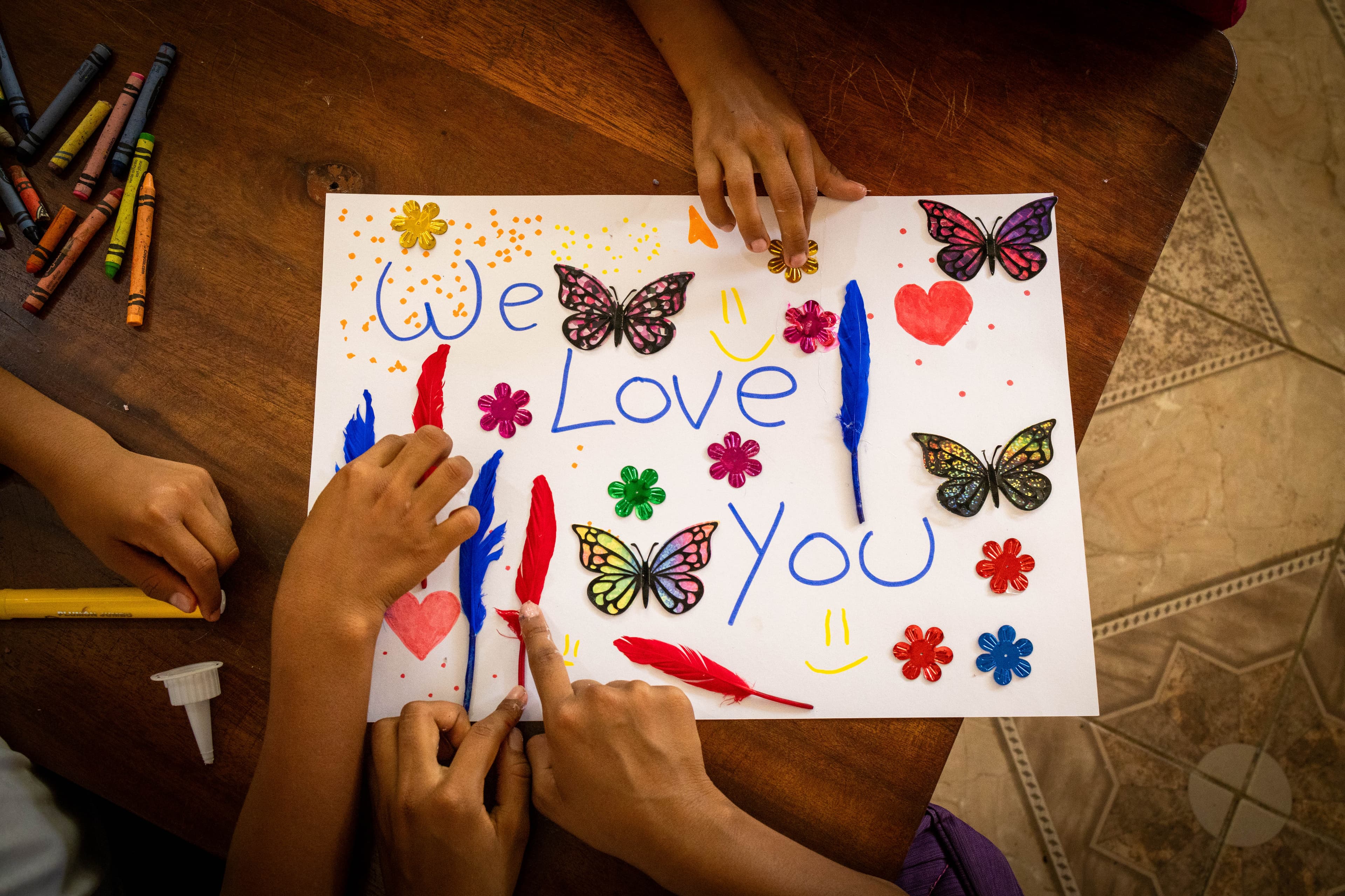 Little hands surround a paper drawing that says “I Love You.”