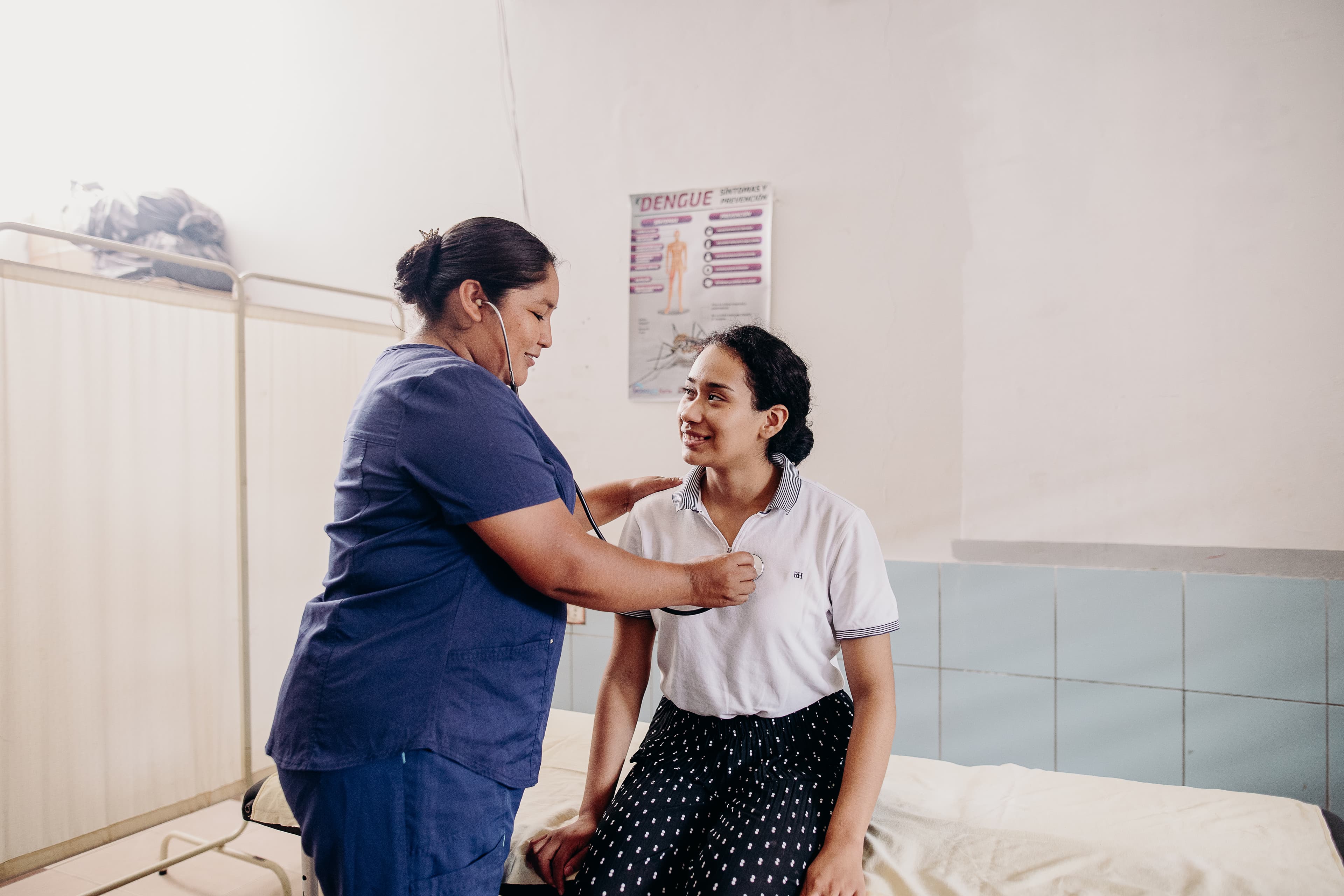 A teen girl has her heart checked by a nurse.