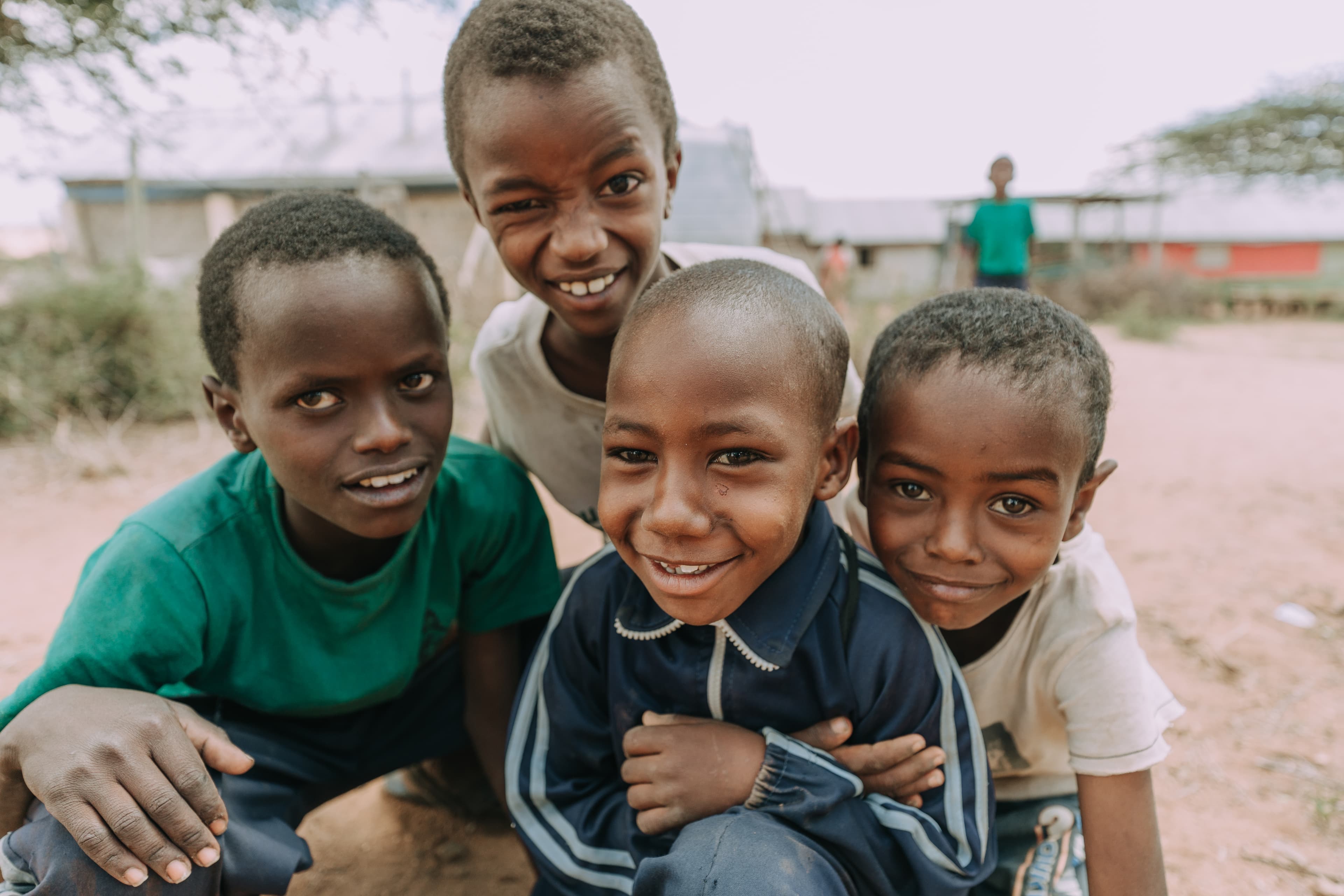 Four young boys are sitting together making playful faces and smiling.