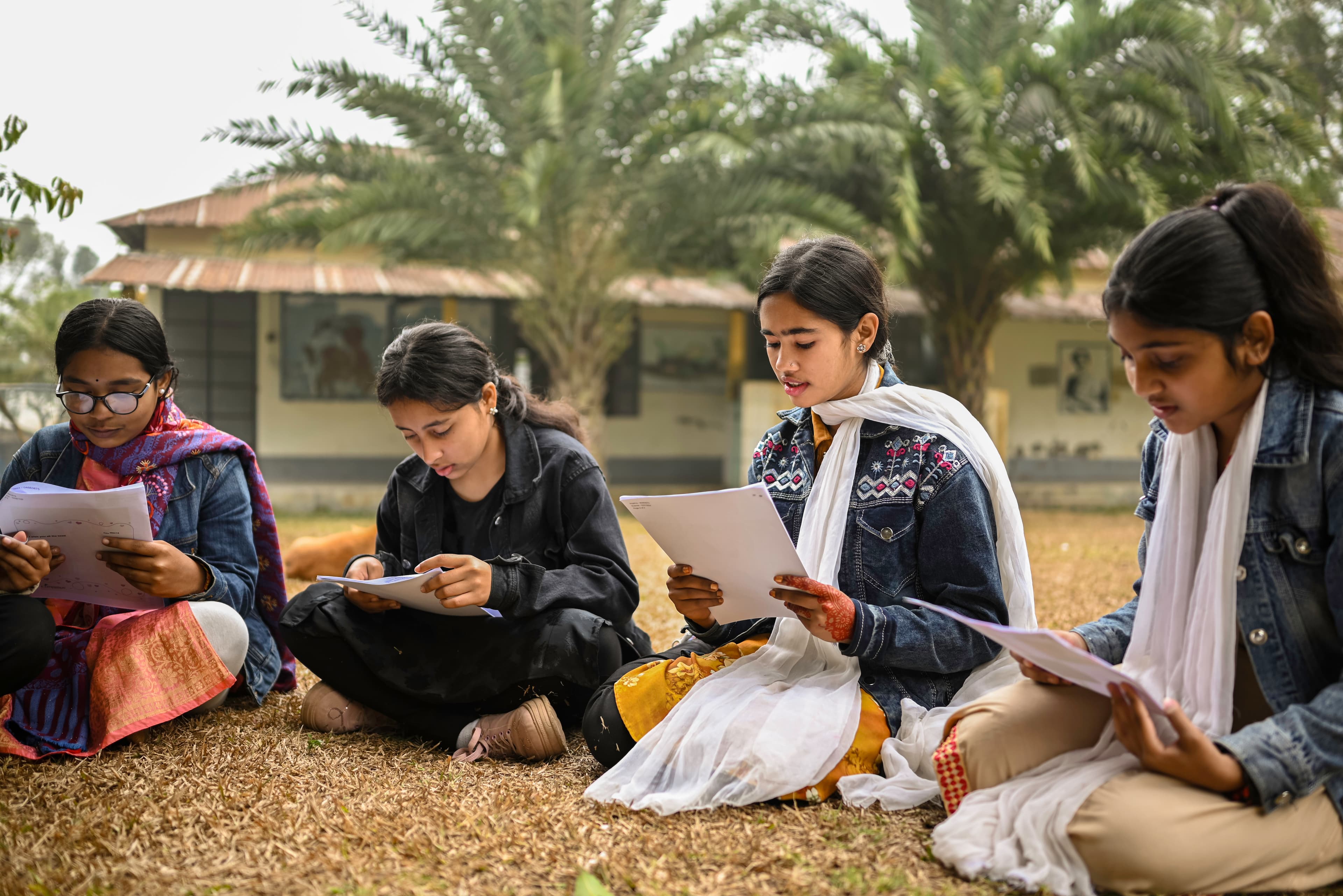 A group of Bangladeshi girls sit and read their sponsor letters.