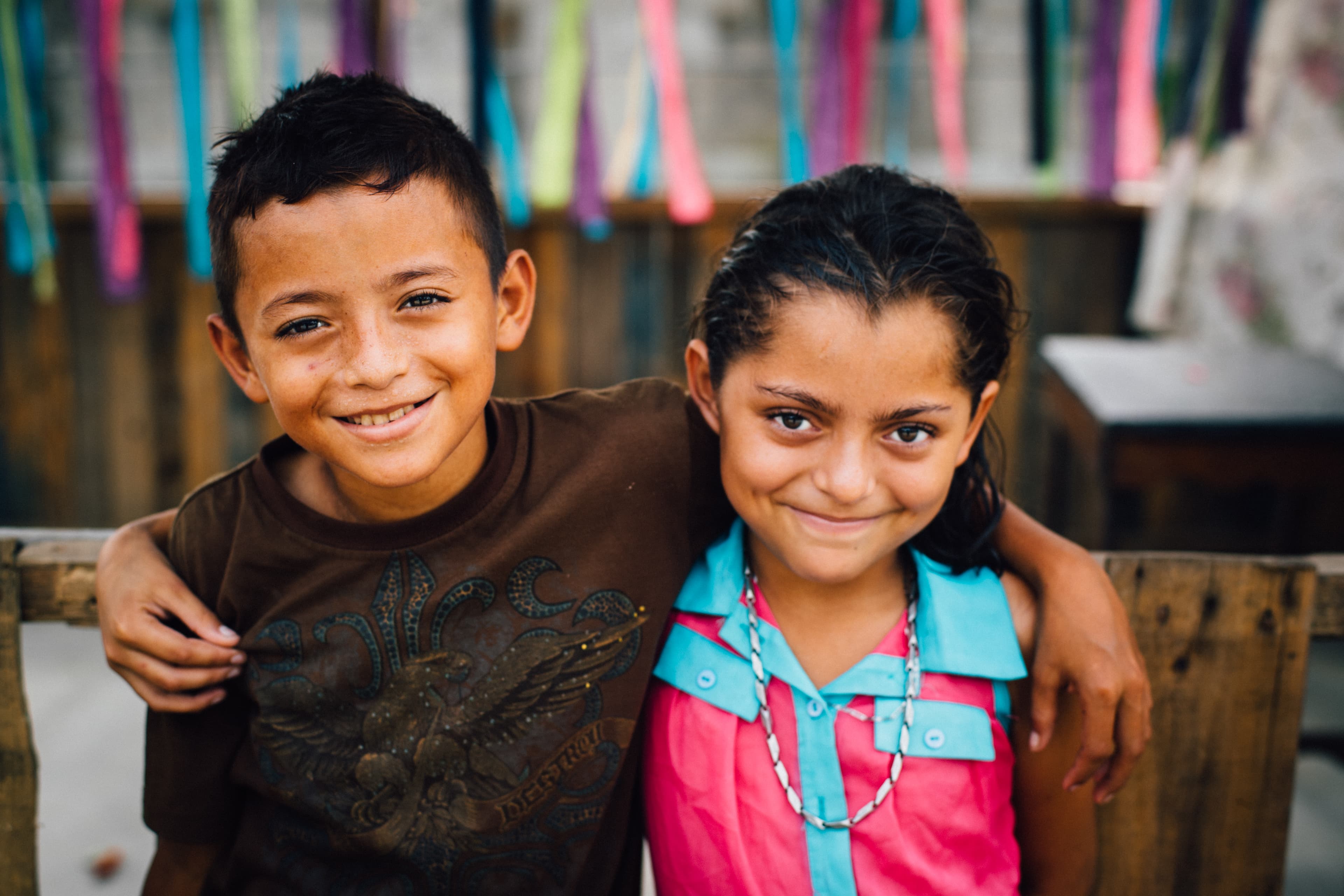 Young boy and girl smile while embracing each other, standing side by