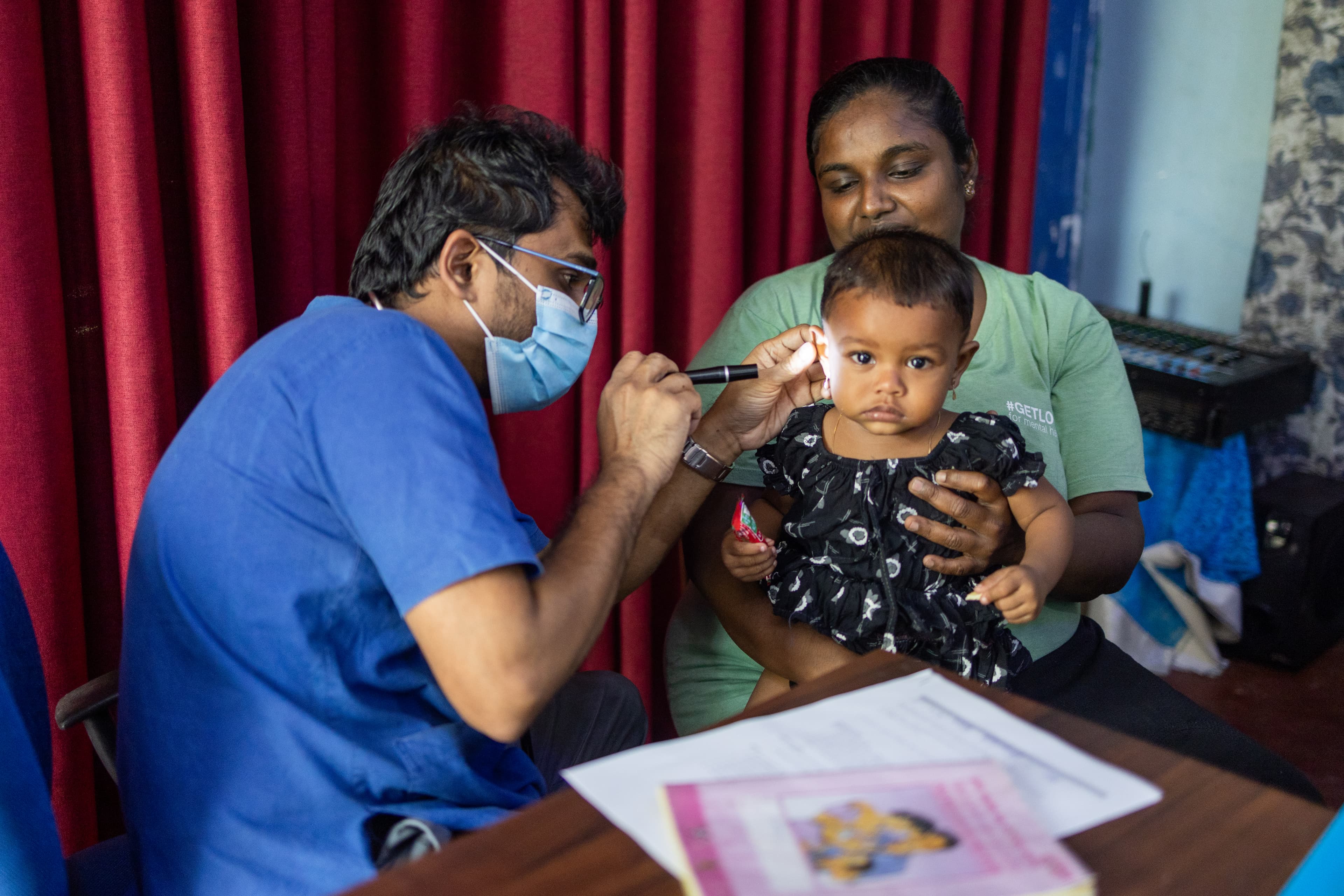 A little girl is sitting with her mother at the center for her medical checkup.