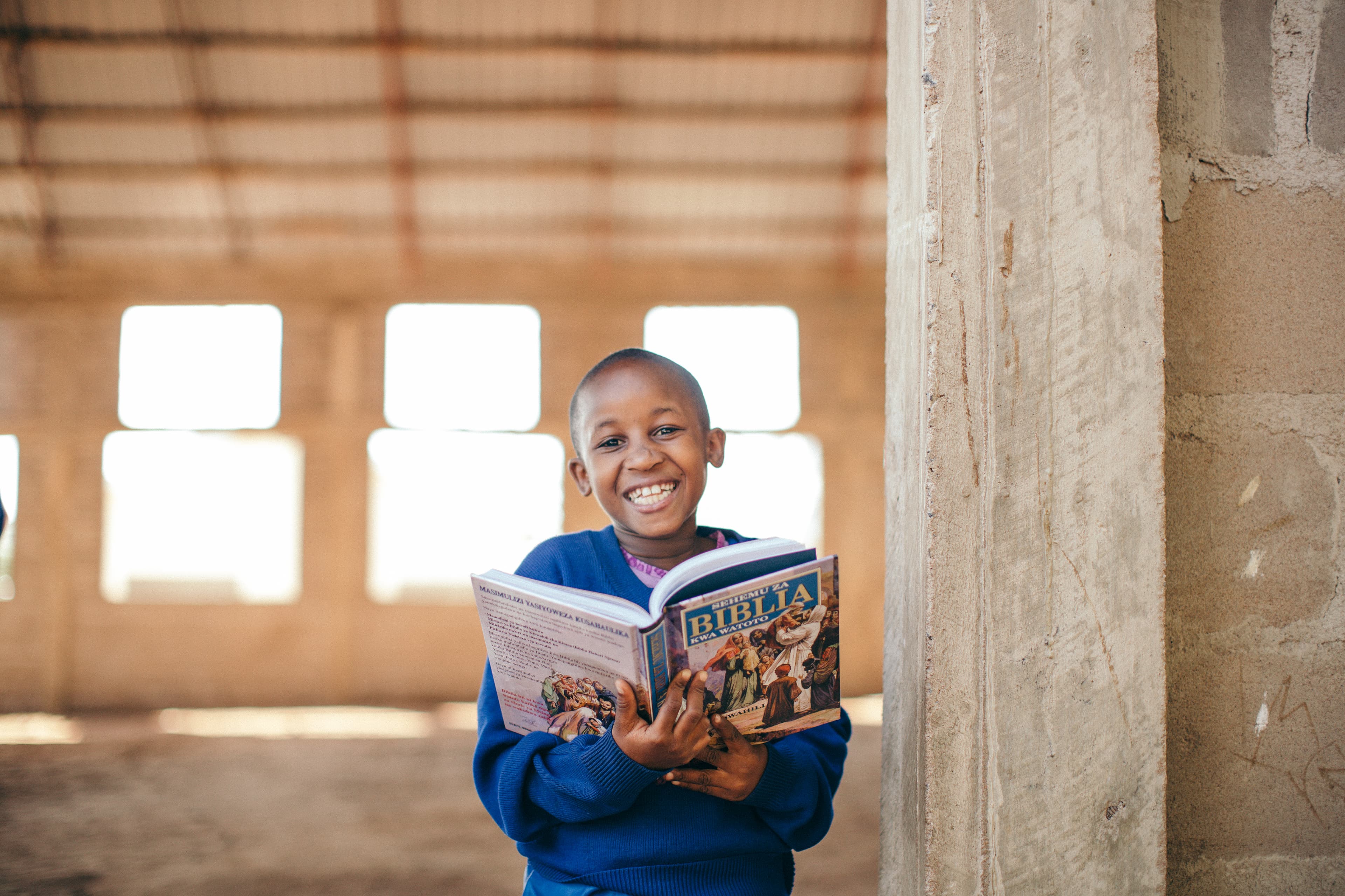 A young girl smiles as she holds a Bible in her hands.
