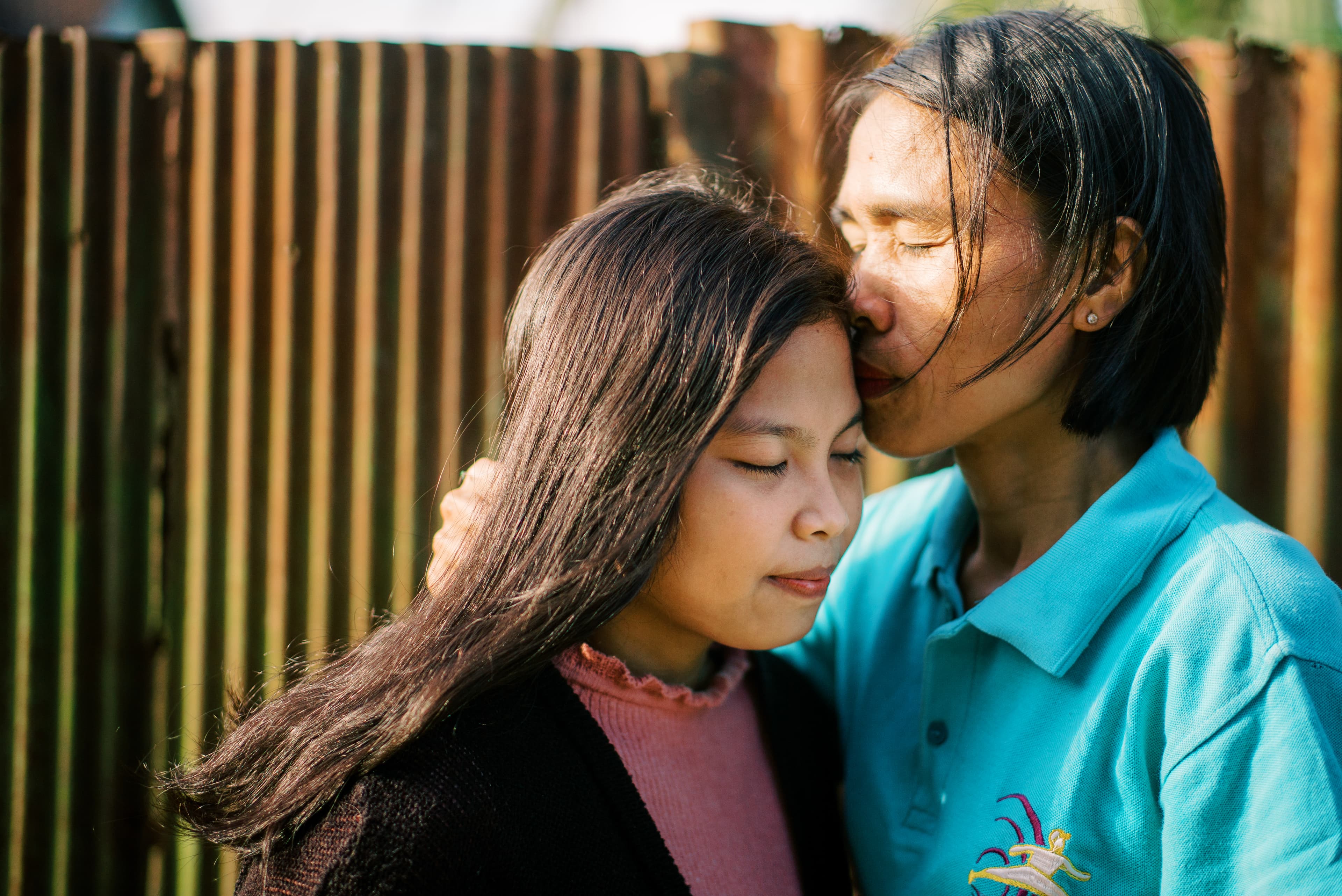 Young girl is standing with her mother.