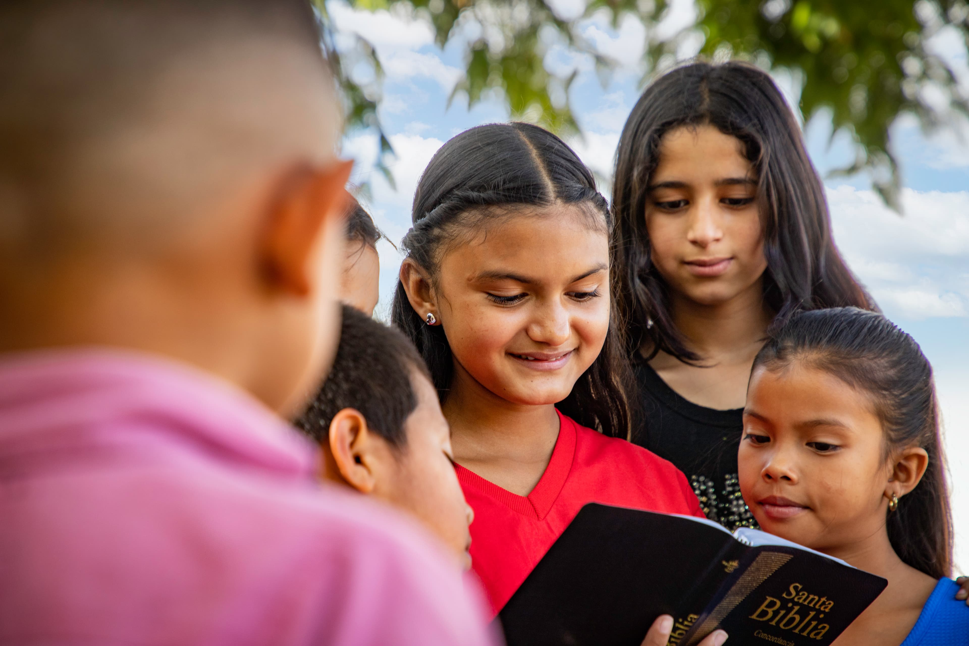 A young girl reads the Bible to her friends