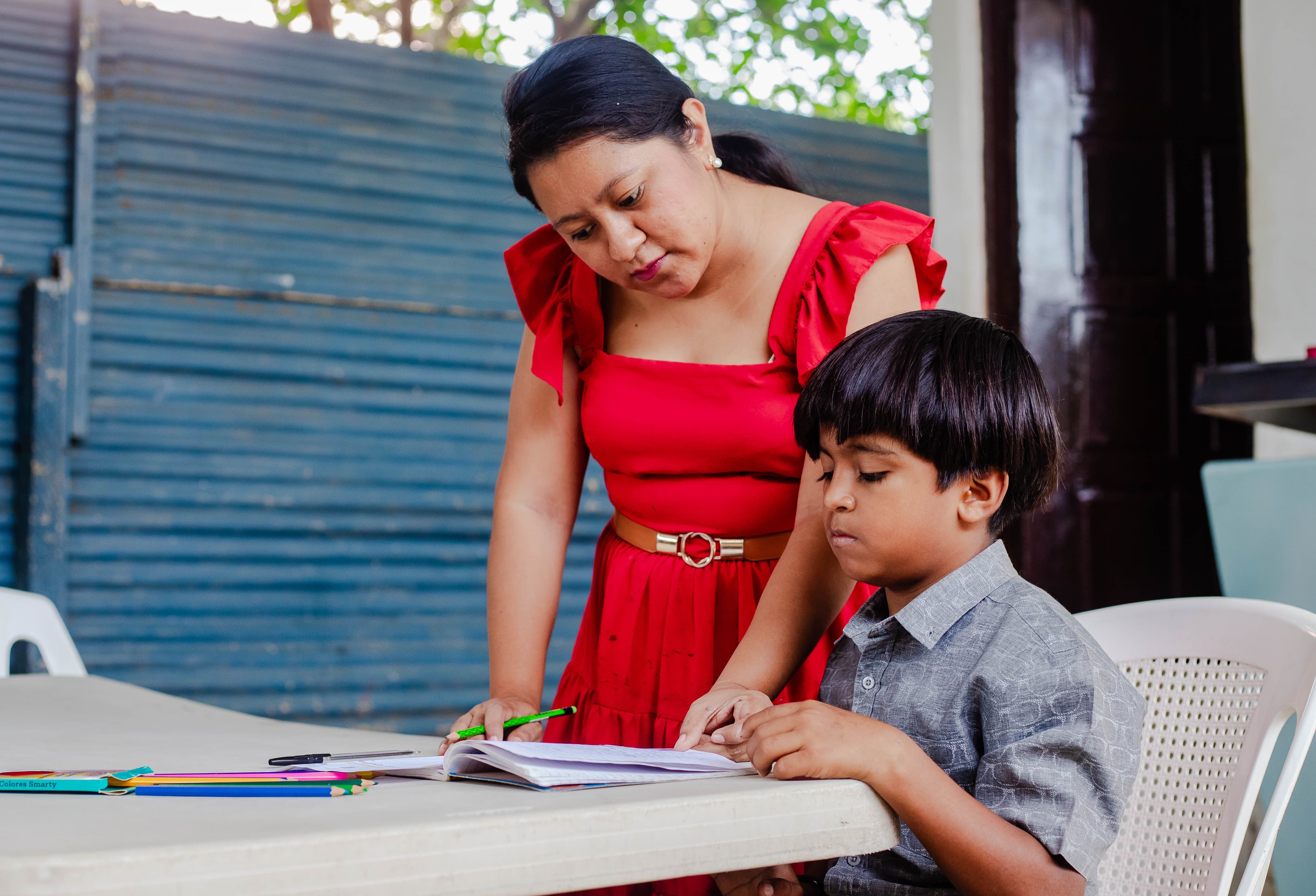 A Compassion center staff member helps a young boy write a letter to his sponsor.