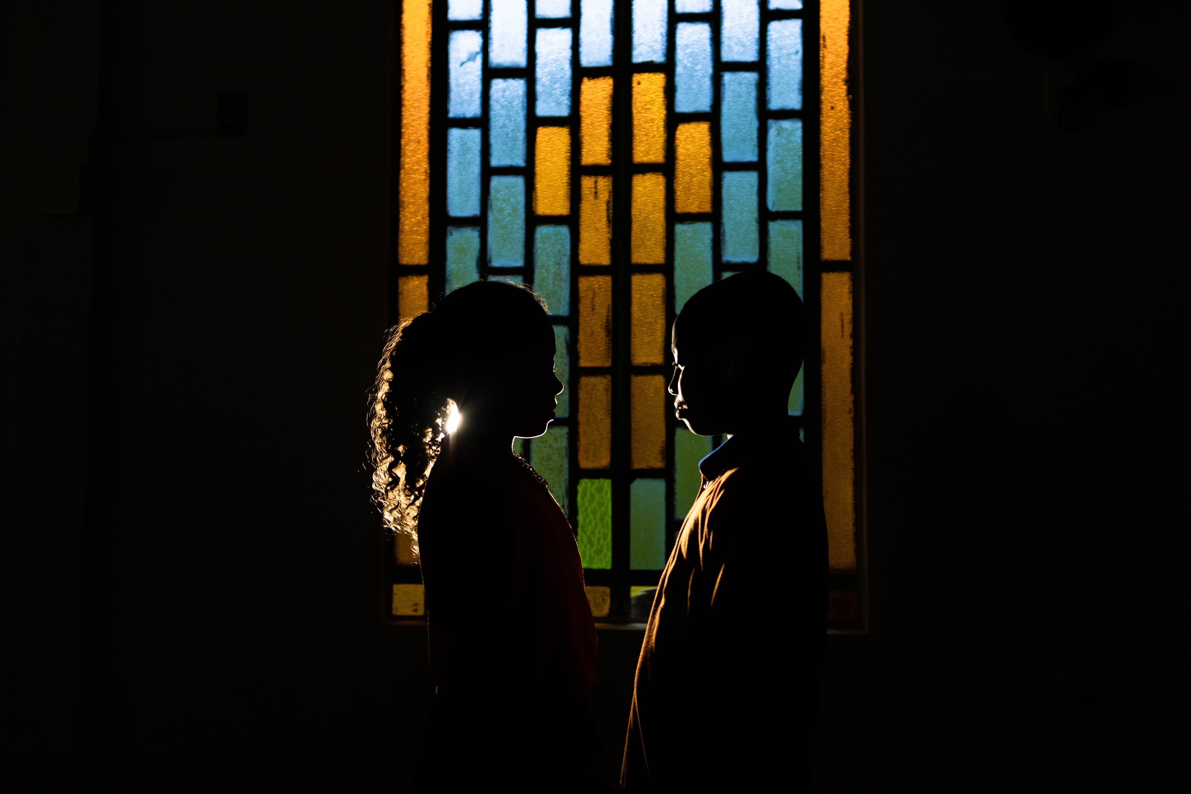 A silhouette of two children in front of a stained glass window.