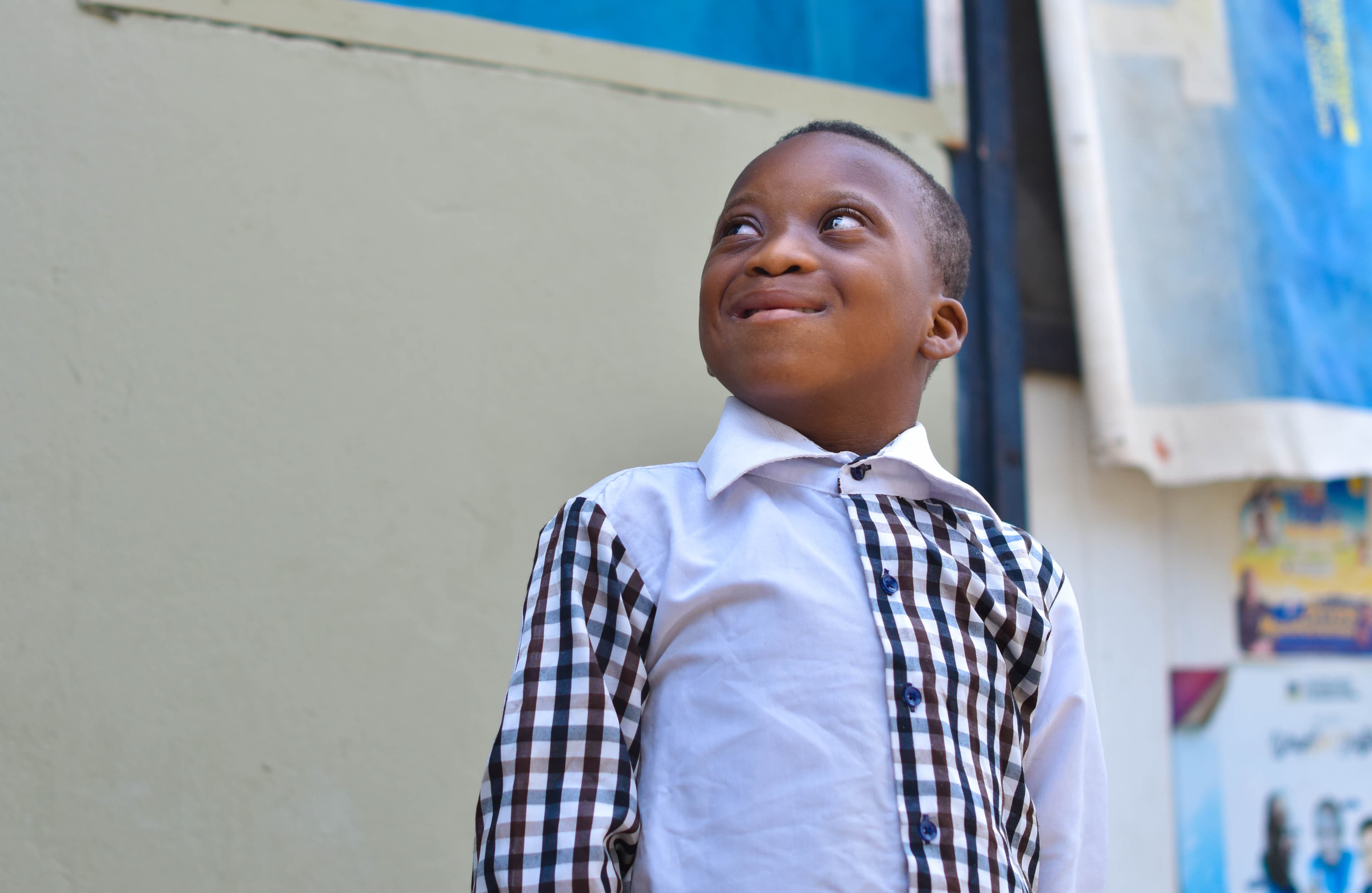 A young boy is standing looking forward with a smile on his face.