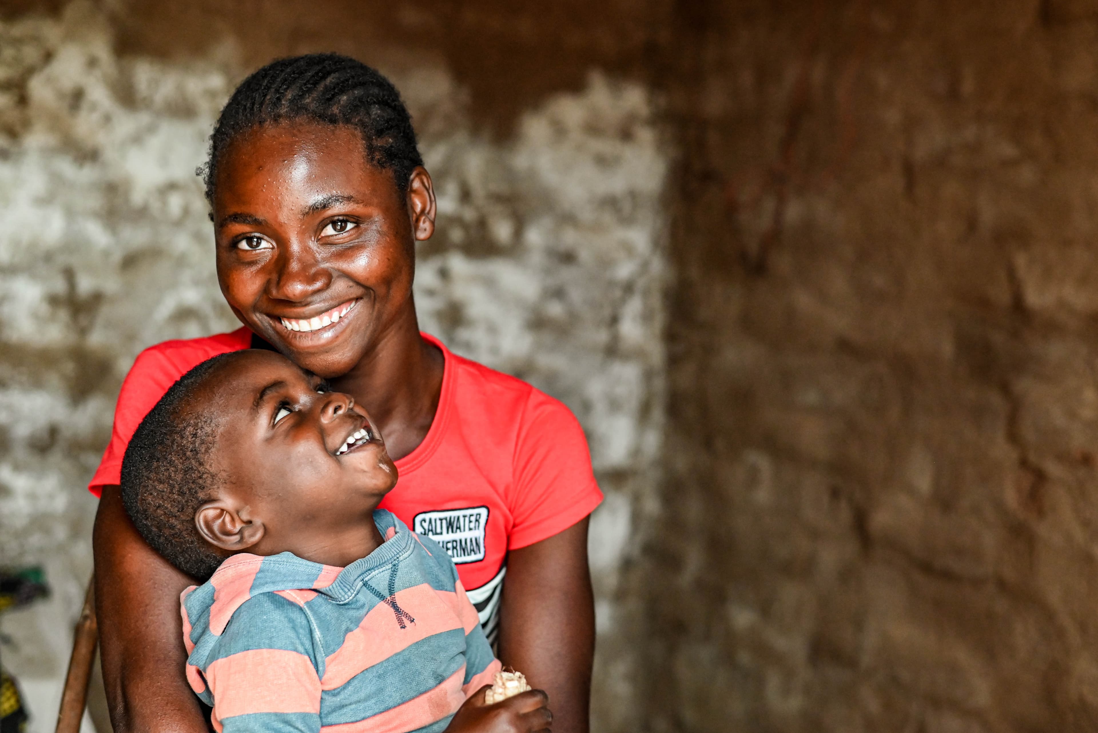 A mother is holding her child who is looking up at her smiling.